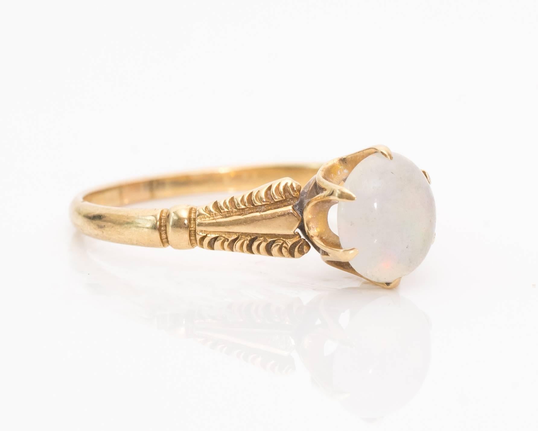 1930s Art Deco Round White Opal 14 Karat and 9 Karat Gold Ring. The large center white opal has stunning red, pink, purple, green, and yellow color play. The stone is mounted in a six-prong talon-prong frame with U-shaped galleries underneath to