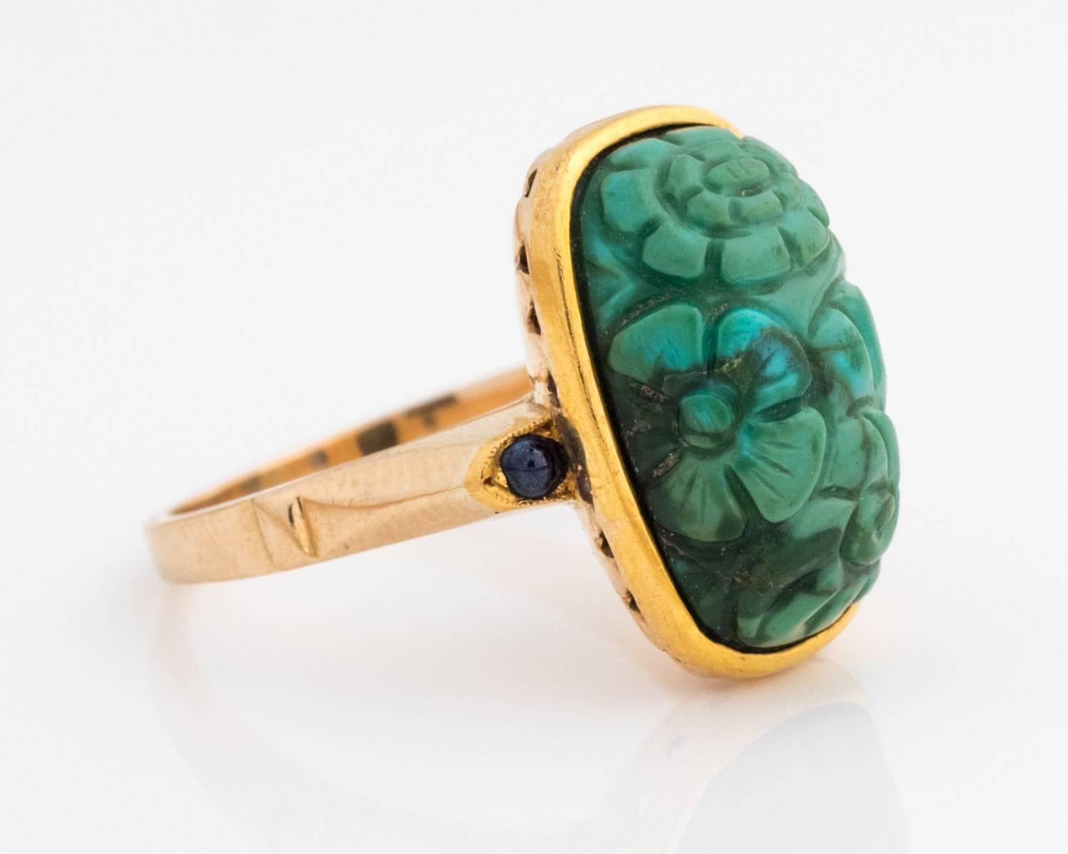 9 Karat Gold
Center Stone is Blue Turquoise Stone, measures 15.3 x 9.1 millimeter
Stone has Green Matte Hues
Ring Features Two Natural Sapphire Round Cabochons, Blue in Color
Along the edge of the Sapphires there are additional milgrain