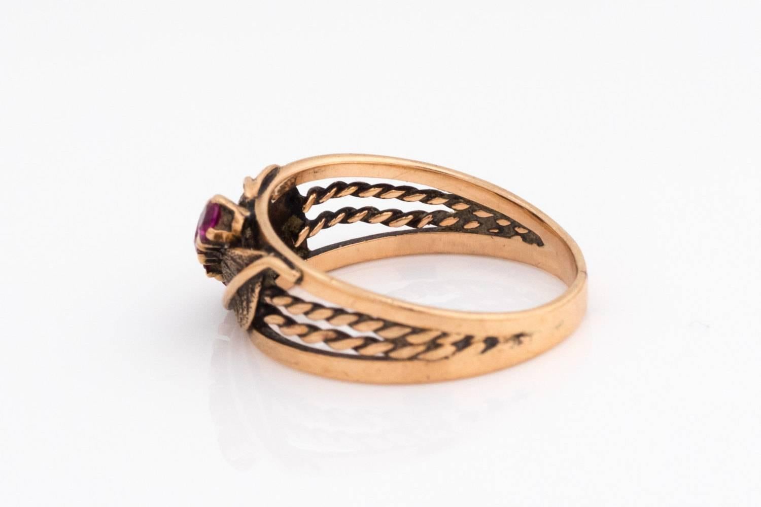 1920s Art Deco Ruby 14 Karat Rose Gold Ring with Elegant Floral Pattern
Stunning Color play between Rose Gold and Magenta Rubies 
Two-Leaf Design Borders Four Linear Placed Simulated Rubies
Braided Double Wire Rope Design Builds up towards the