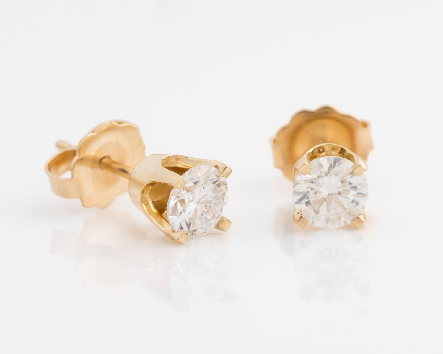 0.65 carats Diamond and 14K Yellow Gold Earrings. The diamonds are placed in four-prong frames with a thick gold frame at the bottom of the prongs. The entire diamond cut is visible due to gaps between each prong. Whatever the occasion, these