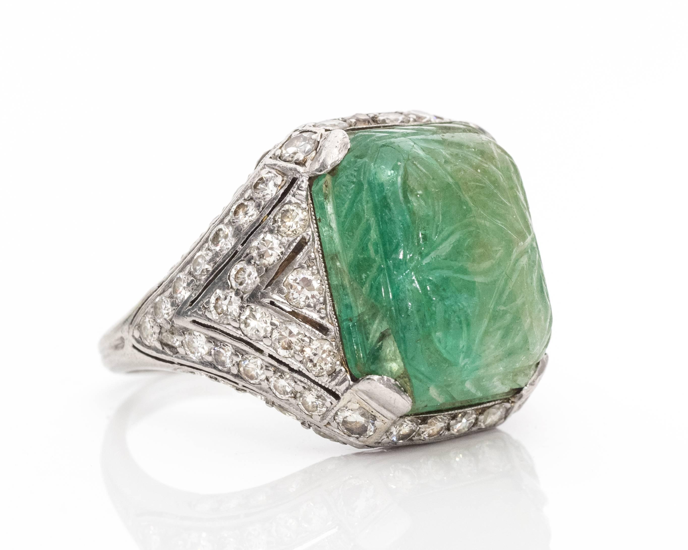 1920s Art Deco Carved Emerald Cabochon Diamond Platinum Ring. A 6 carat emerald is rare for any standards, but a cabochon cut with handmade carvings makes it even more rare and unique. 
The emerald has floral leaf etchings on the stone to complement