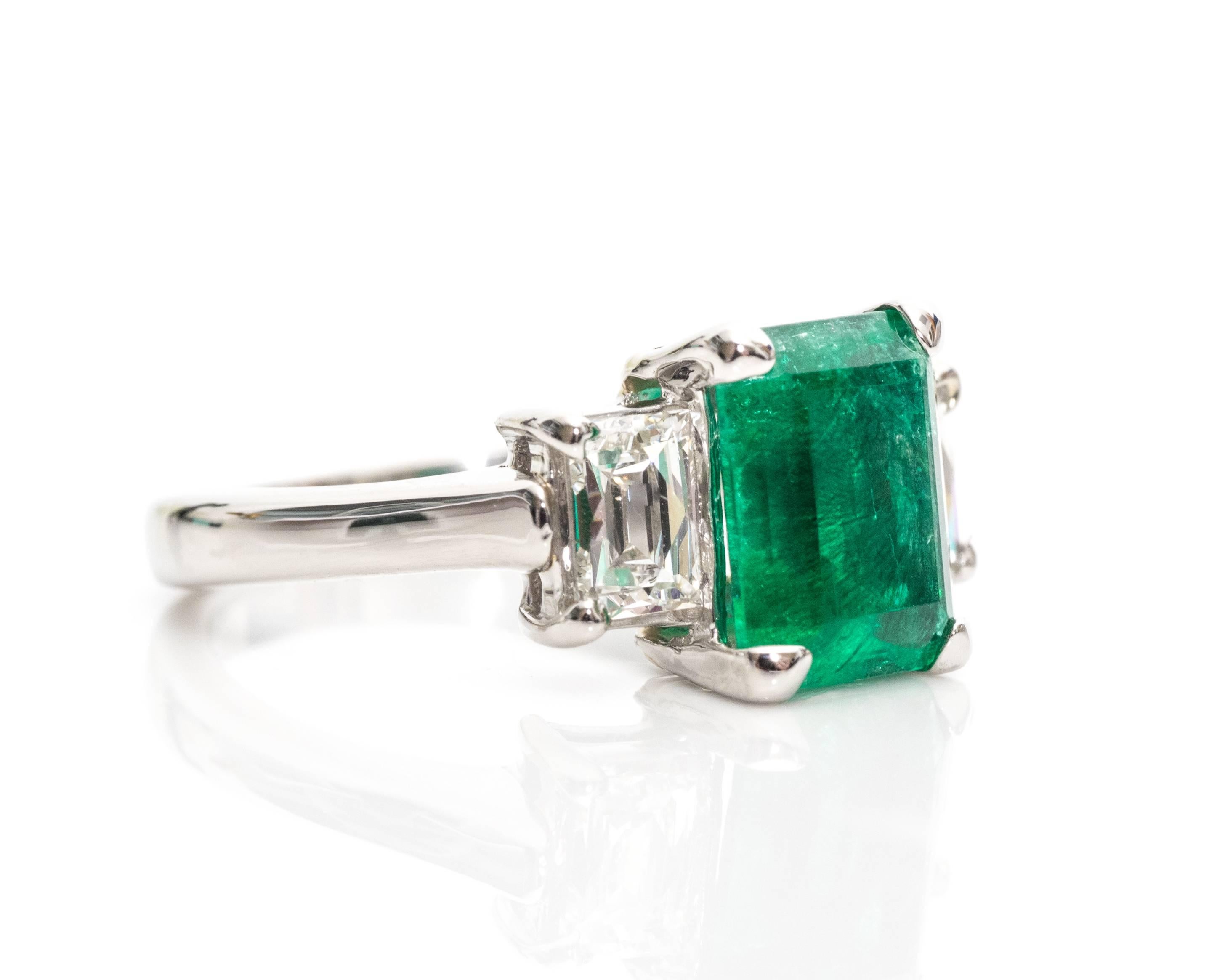 A stunning 1992 engagement ring from the brand Tycoon featuring a gorgeous Columbian Emerald and stunning sparkly diamonds, all crafted in platinum! 

The center emerald has a traditional emerald shape gemstone, Columbian origin, in a four-prong