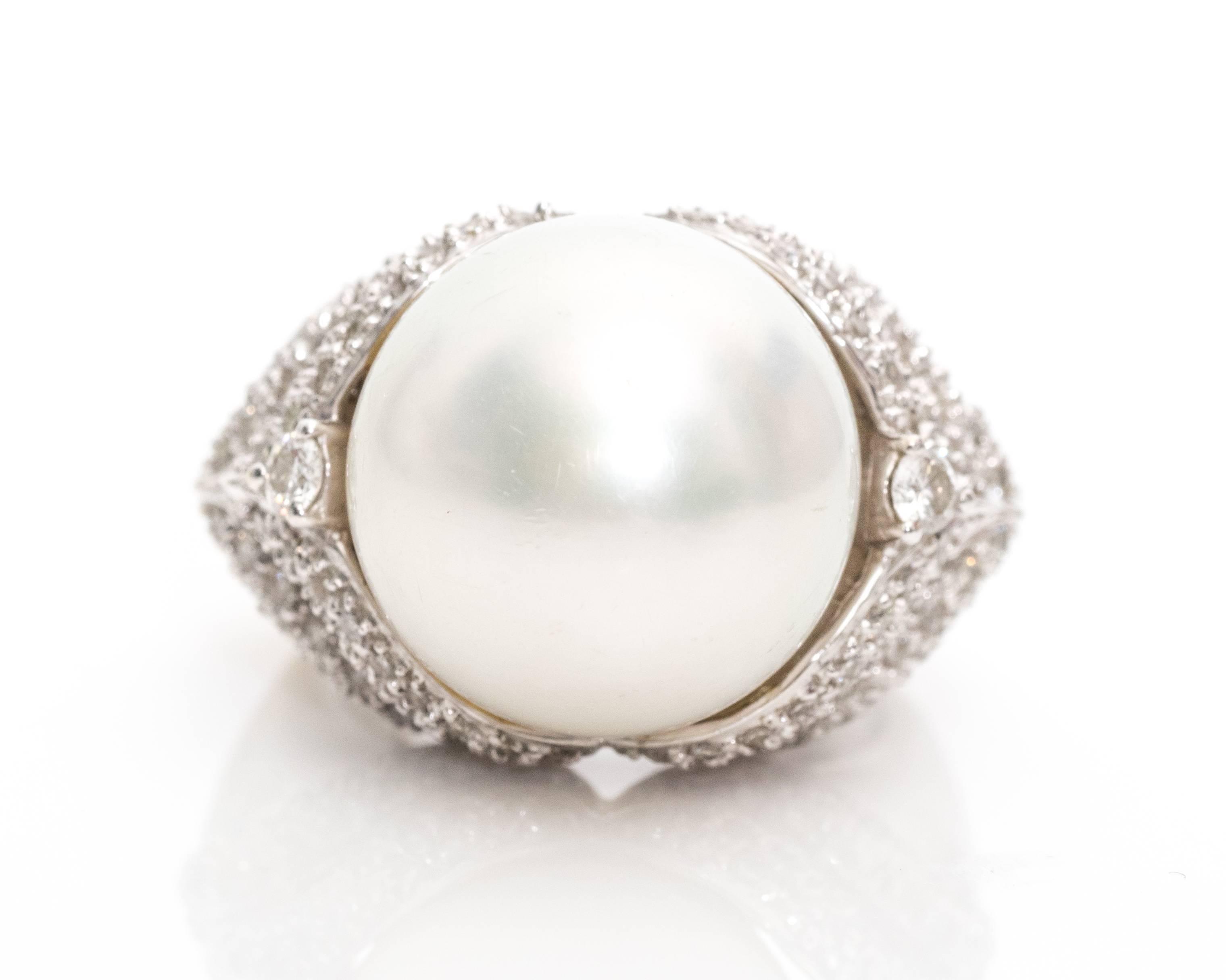1950s Cultured Pearl, Diamond, and 18 Karat White Gold Cocktail Ring

This retro cocktail ring from the 1950s has a large 15 millimeter cultured pearl in the center. There are two diamonds set in three-prong frames on each side of the pearl, with