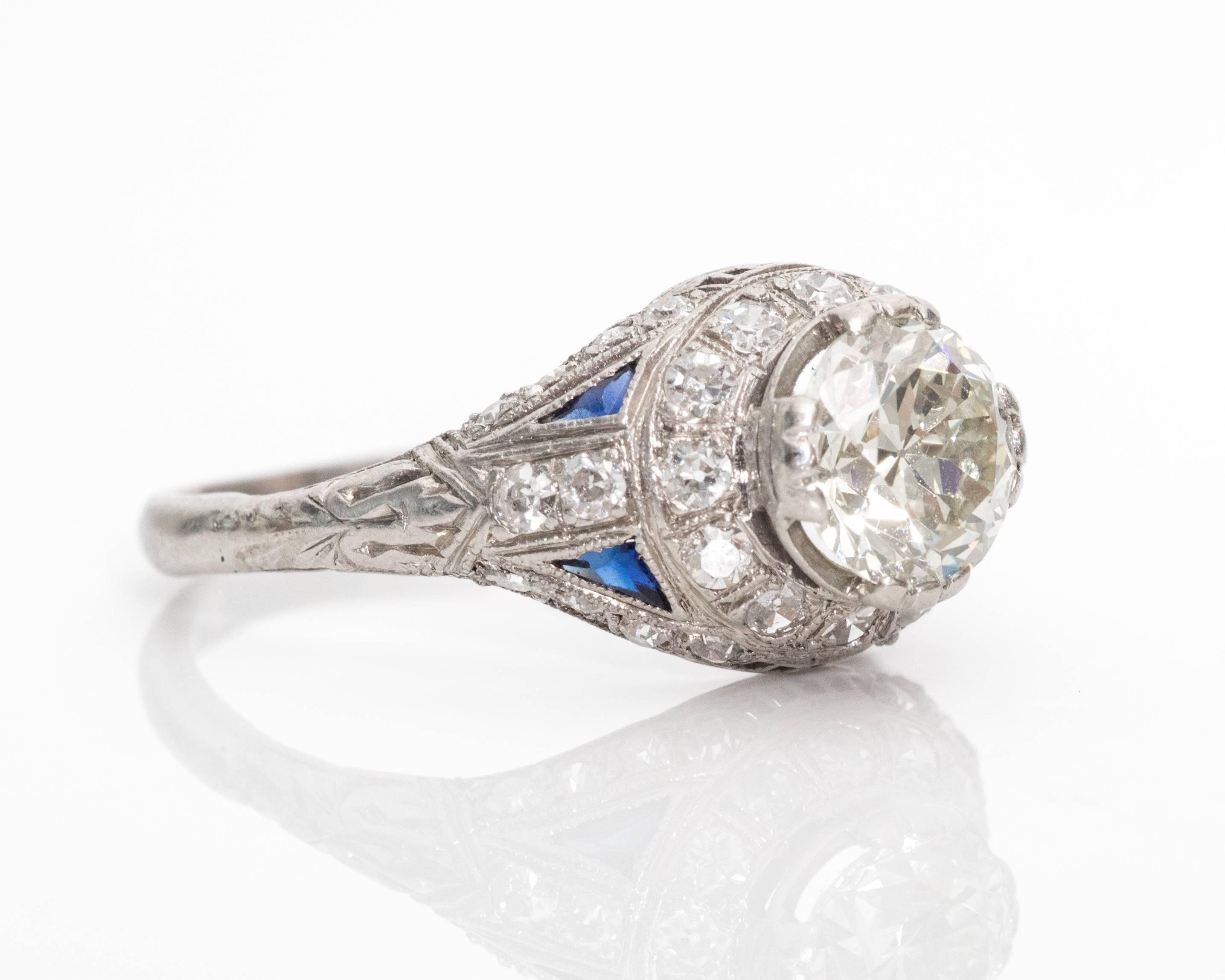 1900s Art Nouveau 1.35 Carat Diamond, Sapphire and Platinum Ring features Trillion Cut Blue Sapphire Accents . The classic cathedral mount is covered in dazzling diamonds all around. The center stone is 1.35 carat with a slight yellow tinge from the