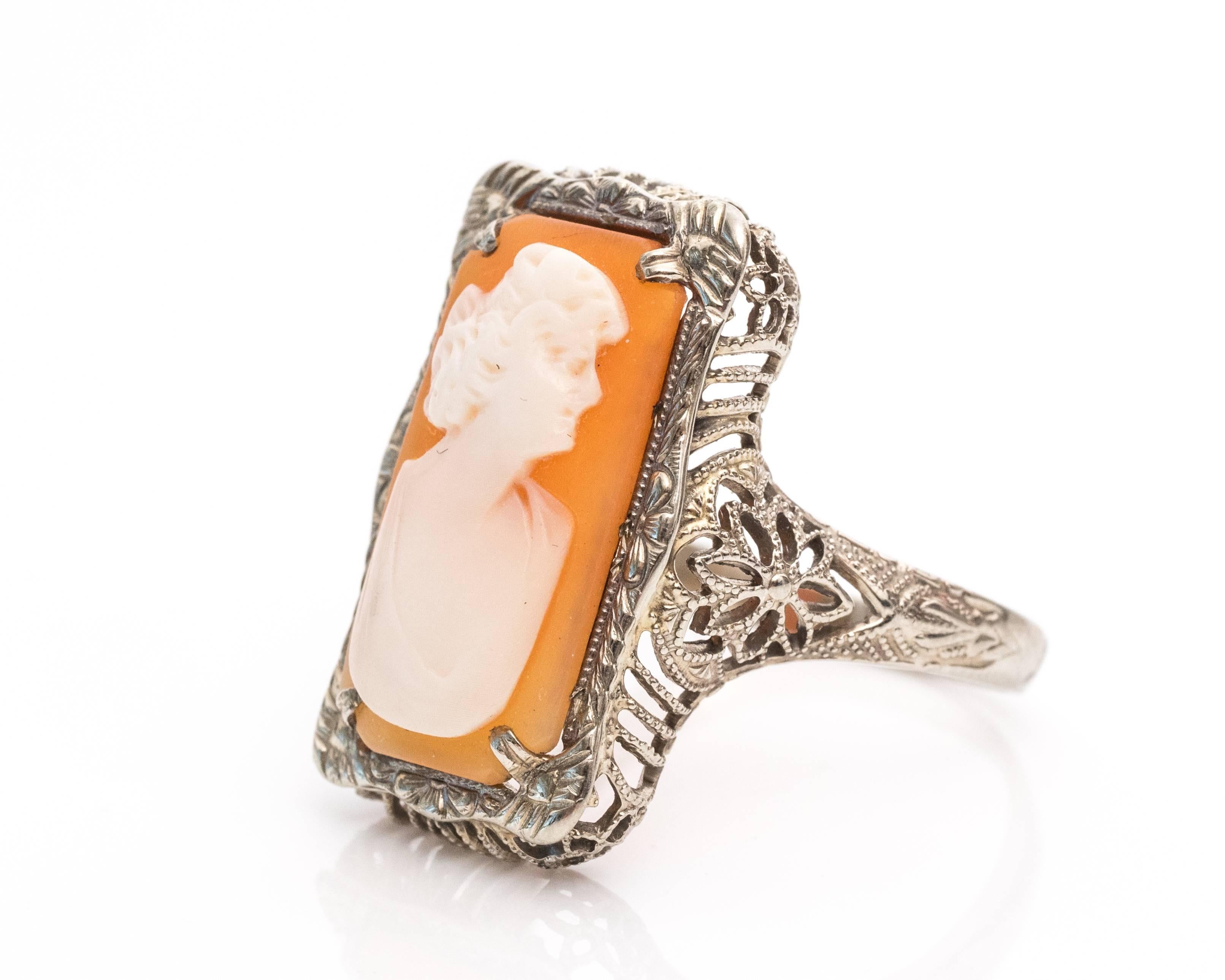 1920s Art Deco Cameo Bust 14 Karat White Gold Filigree Ring
The soft colors and exquisite detail of a carved cameo will remain beautiful through the years.
Depicts a woman's bust in white with a peachy pink backdrop. The cameo is a narrow