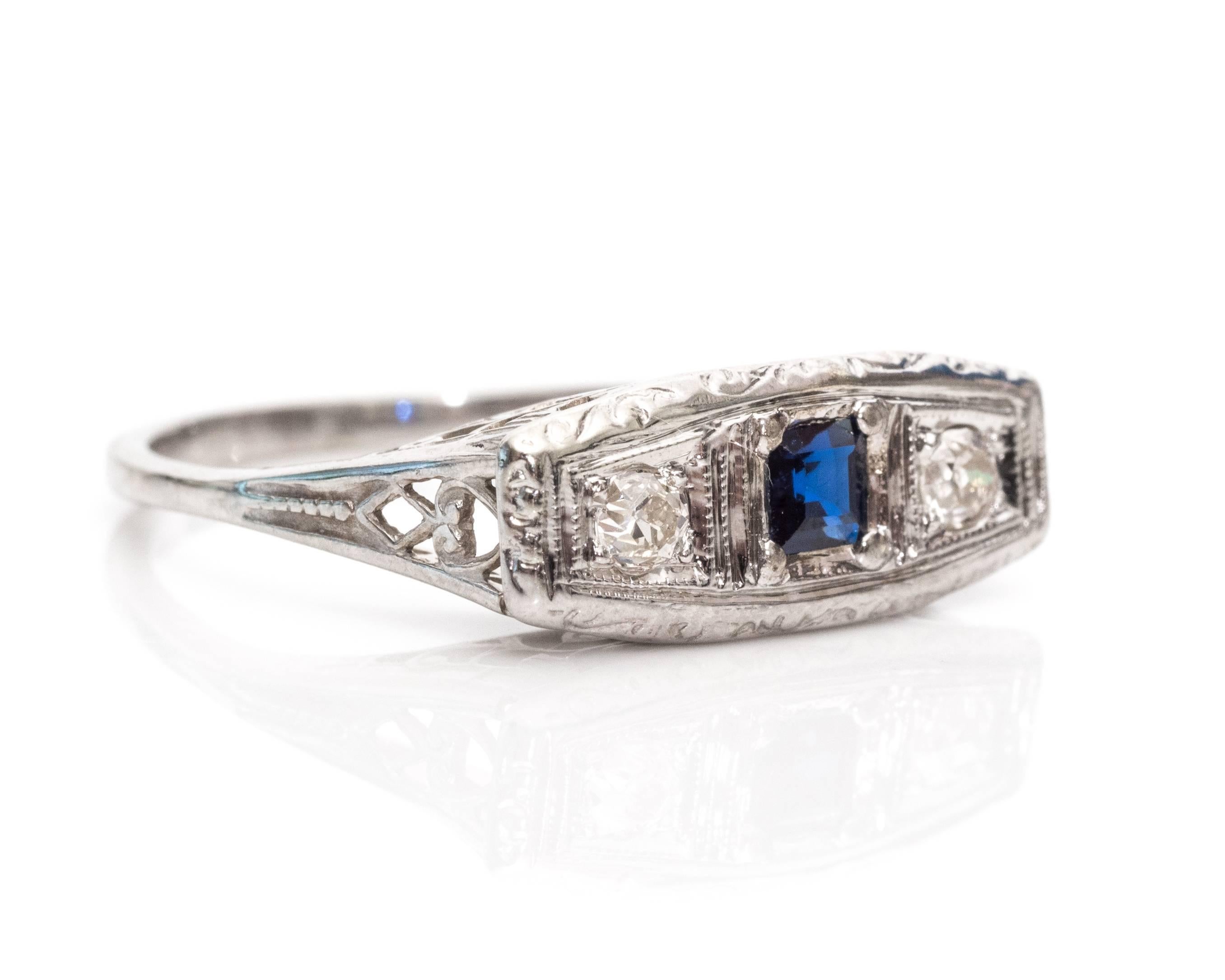 1930s Edwardian Simulated Sapphire Old Mine Diamond White Gold Ring. This ring has a high east-west mount with three stones in the middle. The center stone is a simulated Asscher shaped deep blue sapphire with two Old Mine cut diamonds at its side.