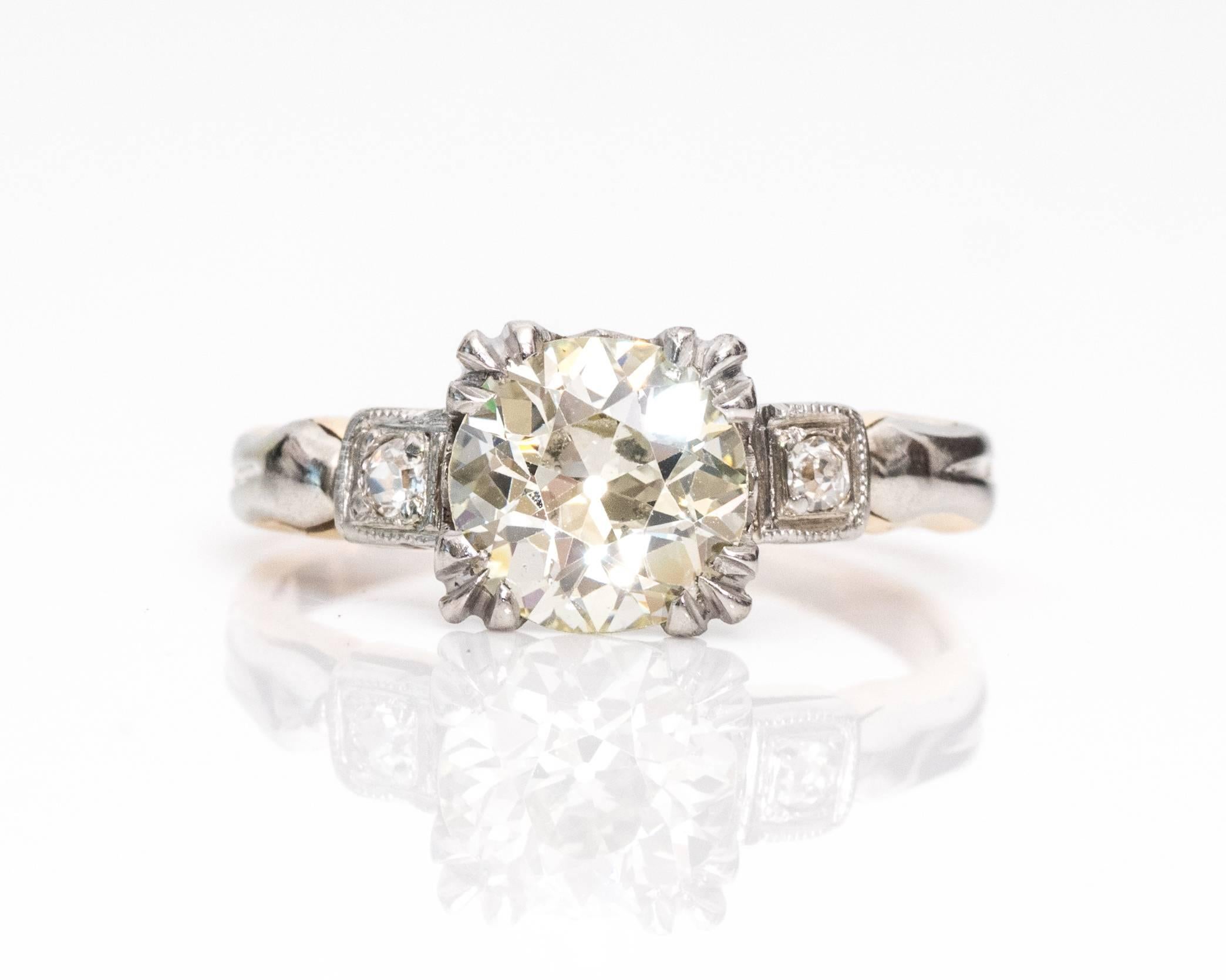  1910 ring features a 1.19 carat Old European, GIA-Certified center stone with fishtail prongs and a small triangle cutout underneath in the gallery. The two diamond accents at each shoulder are Old Mine cuts that total to .02 carats. They are