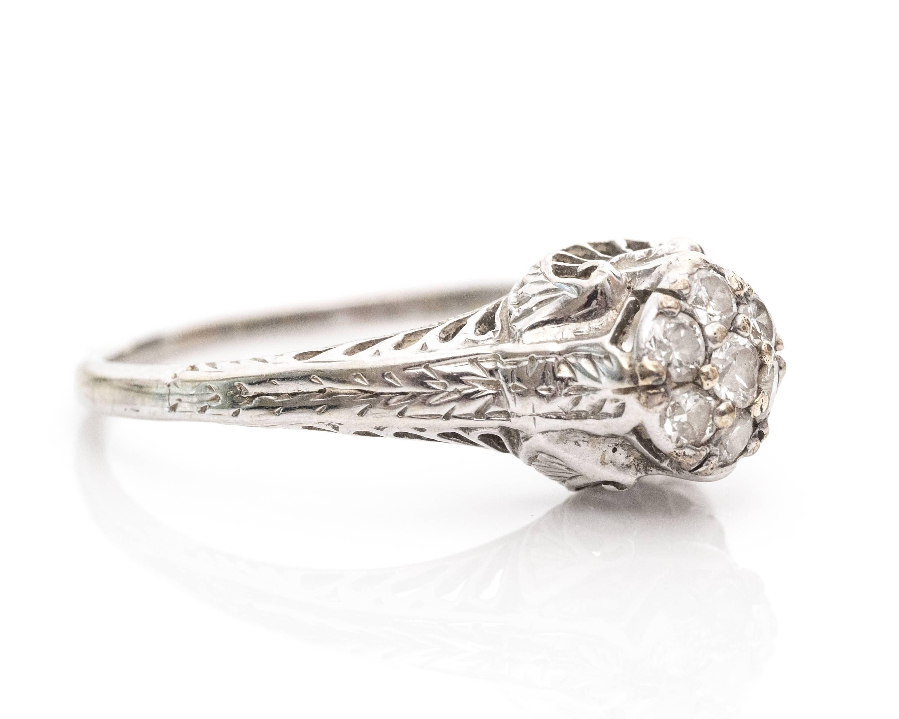 1920s Art Deco .30 Carat Diamond Cluster High Cathedral 18 Karat White Gold Ring. A traditional cluster ring full of charm! This 1927 engagement ring has seven diamonds totaling to .30 carat. The round stones are inlayed at the top of the ring with