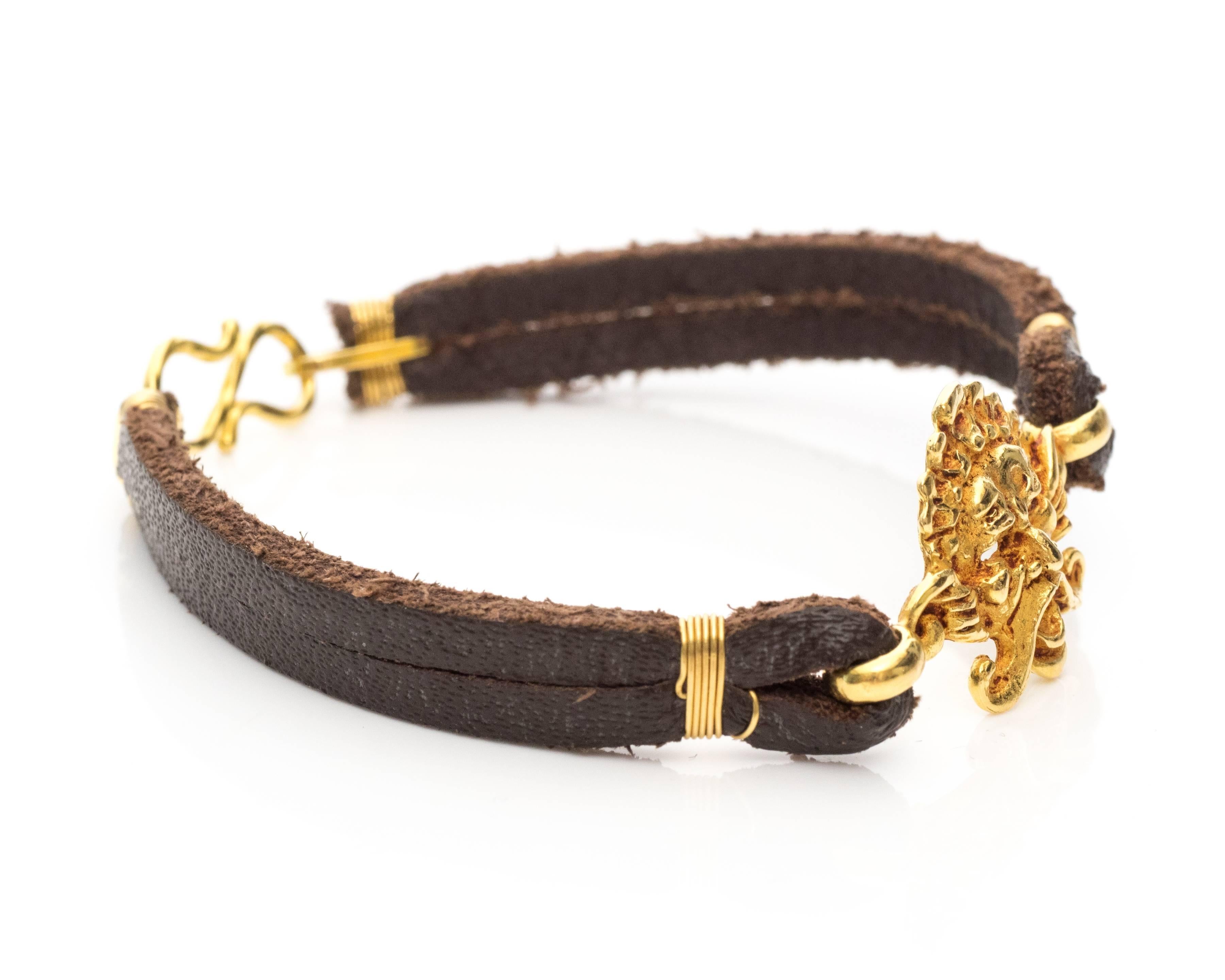 We love this fun and unique bracelet! It was handmade by a jewelry artisan and features a leather band with an S-lock clasp and a 22 karat yellow gold character mask. This bracelet will fit a 7 inch wrist  and weighs 9.6 grams.

Item Details:
Metal: