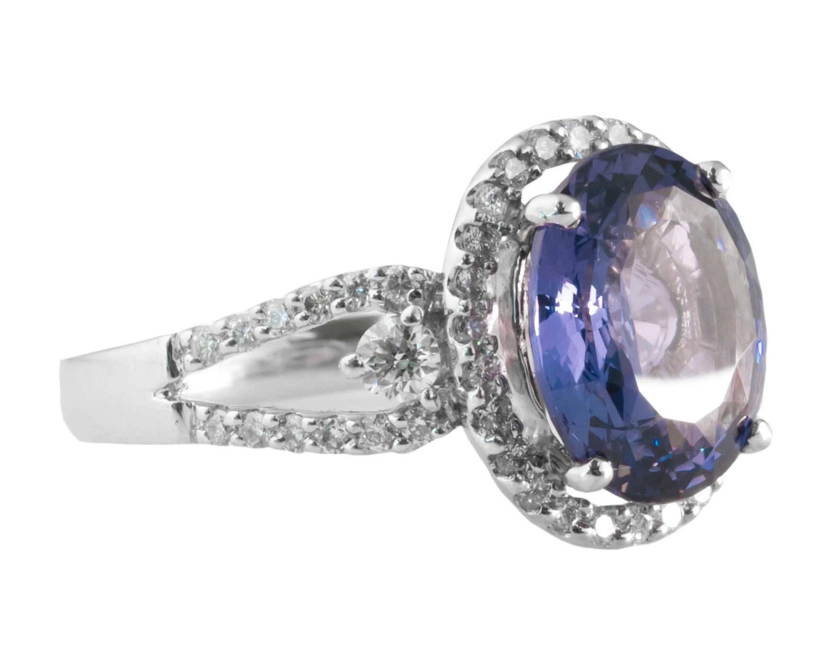 Modern Sapphire and Diamond Cocktail Ring from 1990s

Center features a beautiful 2 Carat Sapphire
Oval Brilliant Cut, Light Blue-Ish Violet Color 
Heat Treatment, Prong-Set

Accent Diamonds make up a Lovely Halo around the Sapphire as well as