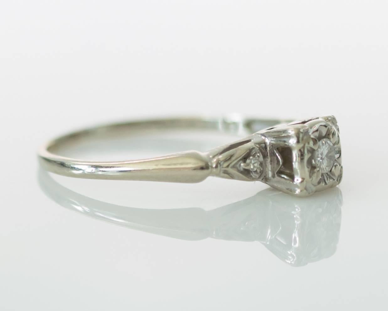 1940s Engagement Ring with a beautiful floral ribbon design and cathedral-style center stone mounting. The ring is crafted entirely in 14 karat white gold with a dainty shank, fitting ring size 7.5 that can be resized up or down two sizes with ease.