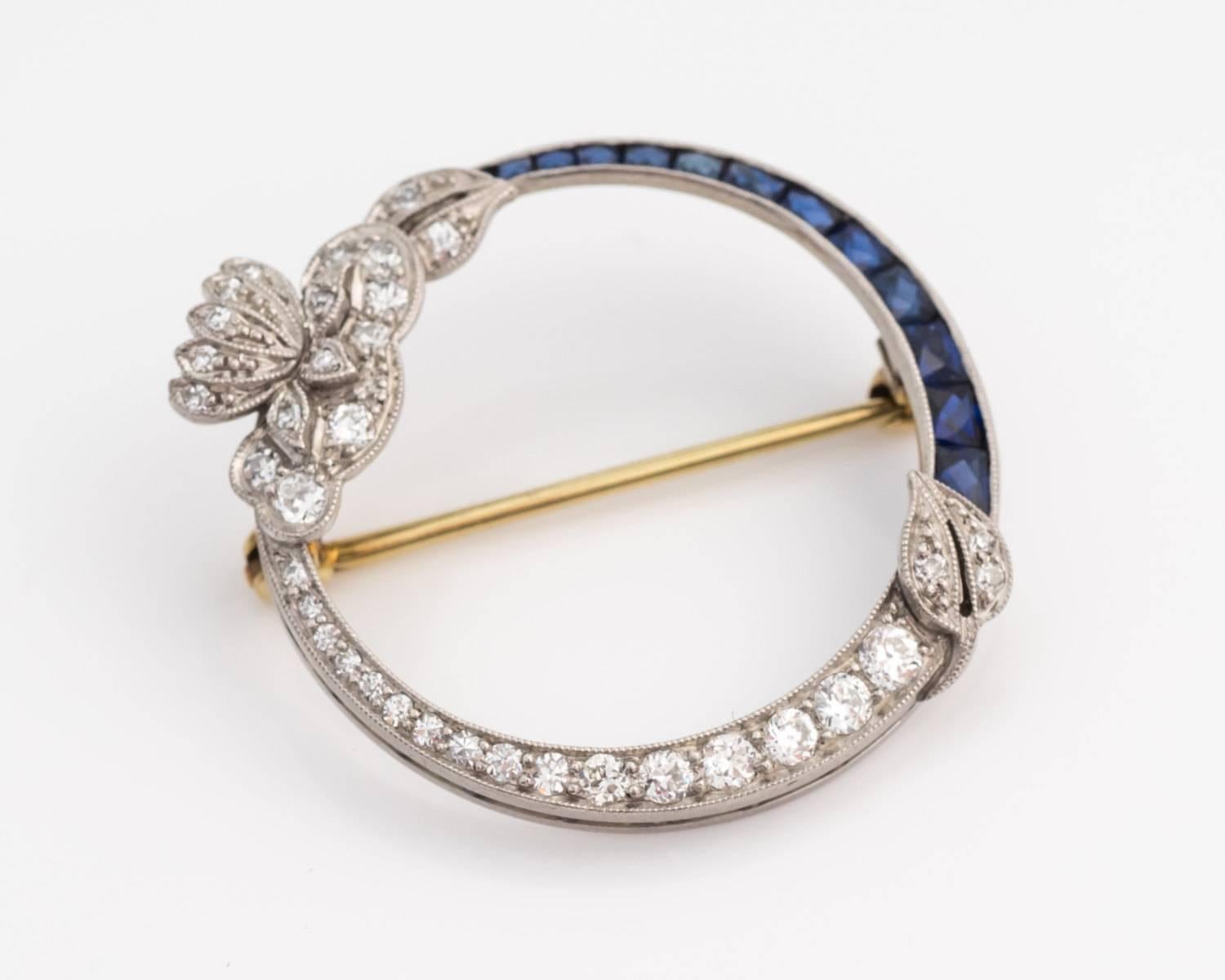 1915 Edwardian Era Brooch, Lapel Pin features French-Cut Blue Sapphires and Round Faceted Single Cut Diamonds graduating down in size.

This lovely pin features a circular design with inlaid gemstones along the frame. At the lower edge of the pin is