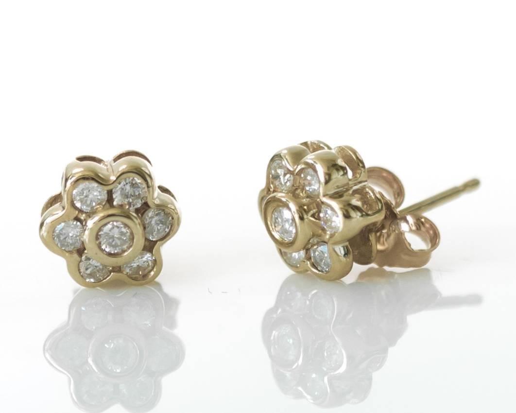 This dazzling pair of floral themed diamond earrings feature 14 diamonds bezel set in 14 karat yellow gold. Featuring friction back posts, these earrings weigh 2.1 total grams. This dazzling pair of floral themed diamond earrings make the perfect