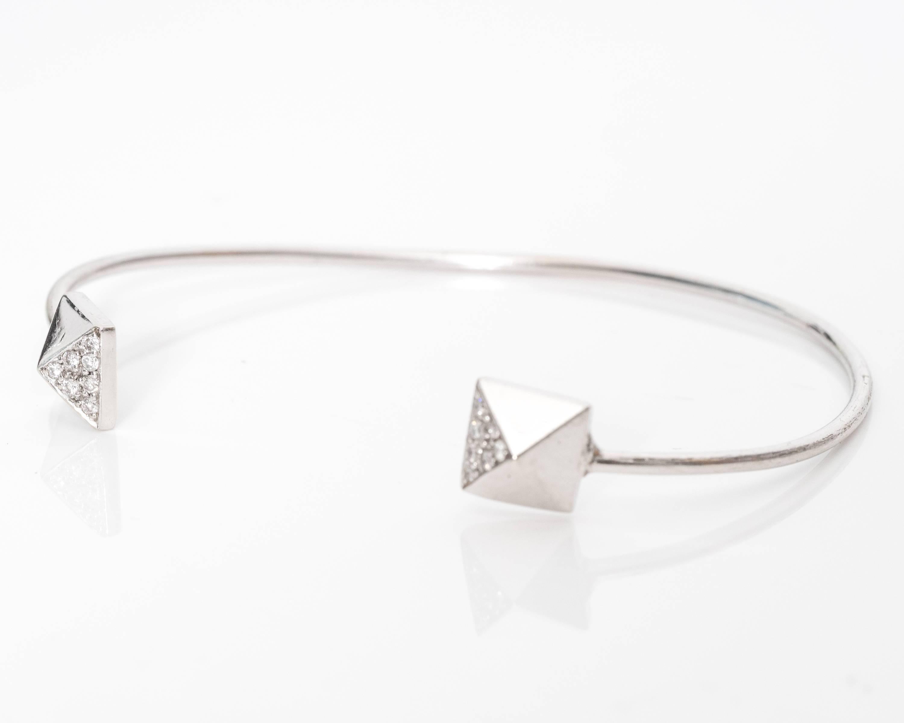 This fabulous bangle bracelet has seven diamonds on each pyramid shaped end accent. The diamonds are set symmetrically along the pyramid shape. The entire bracelet has a shiny white gold hue with a thin frame. It's perfect to wear with other