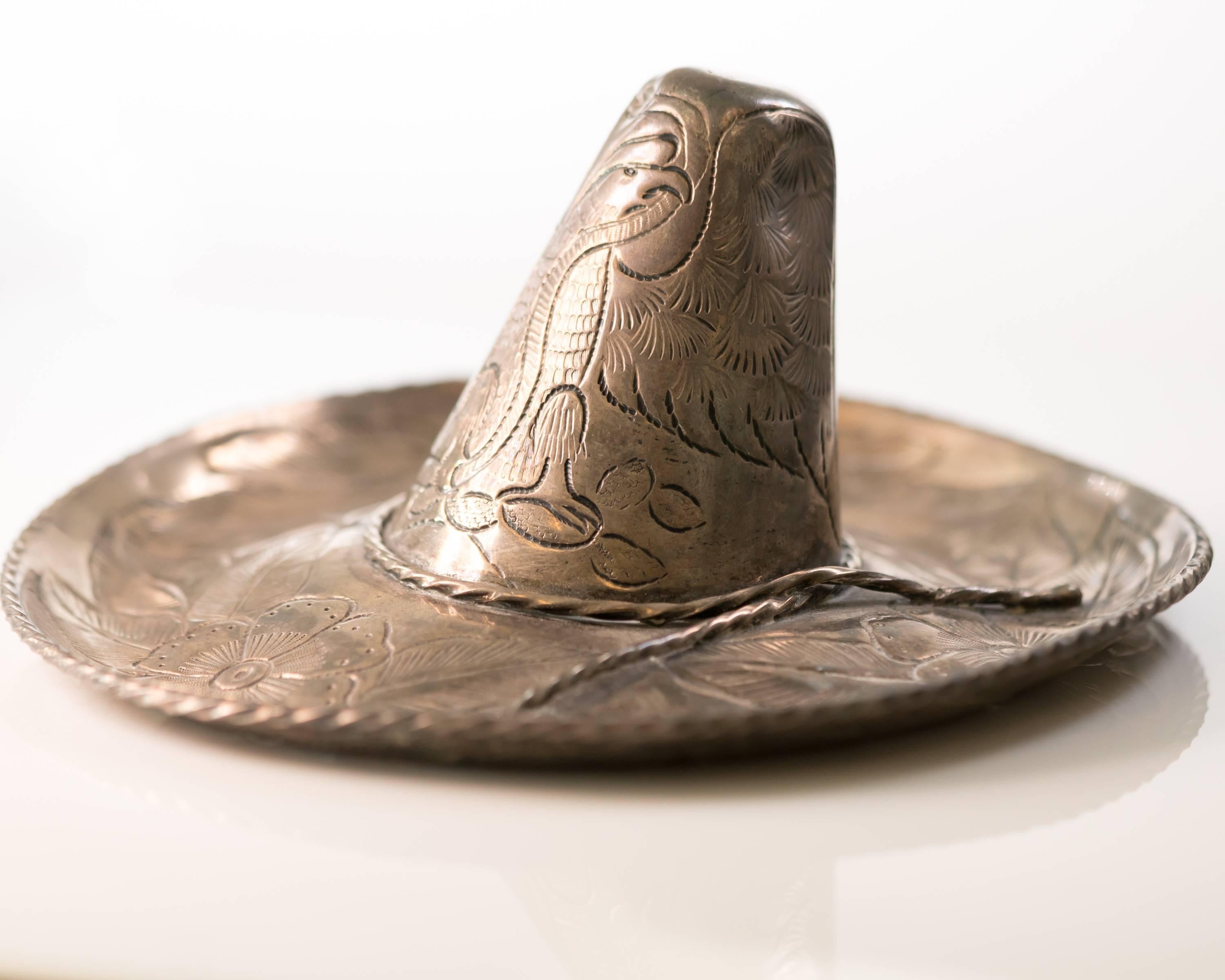 This 1950s Retro Hand Engraved Sterling Silver Sombrero was created by Mexican artist L. Maciel from .925 sterling silver. The upper and undersides of the sombrero are engraved with a floral design and the rim has a handsome rope design. The Eagle,
