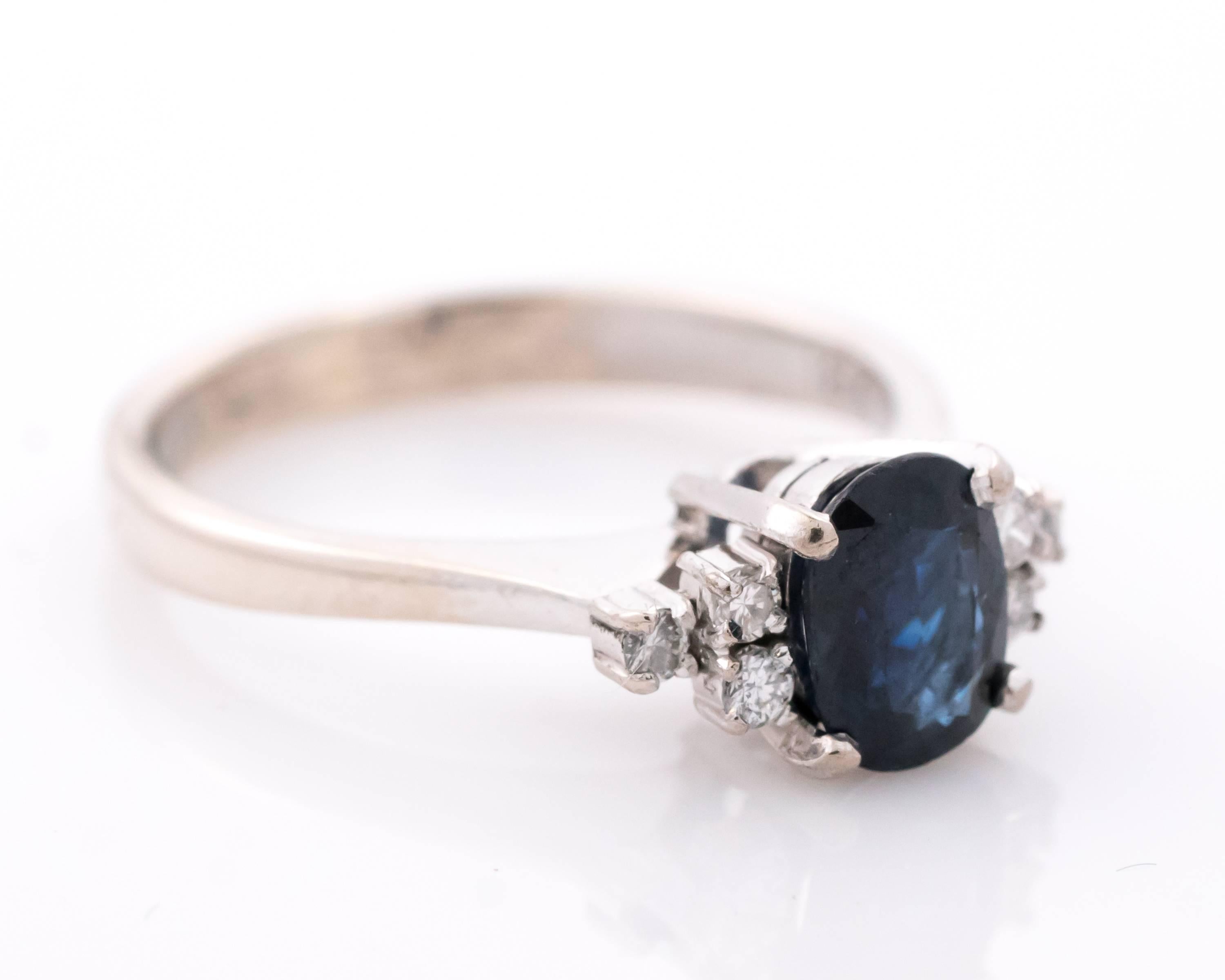 This 1950s retro vintage Blue Sapphire and accent Diamond Ring features a Cathedral Setting with Gallery. The 1 Carat Oval Blue Sapphire center stone is flanked by 6 round brilliant Diamonds, 3 on each side - perfect add of sparkle to the