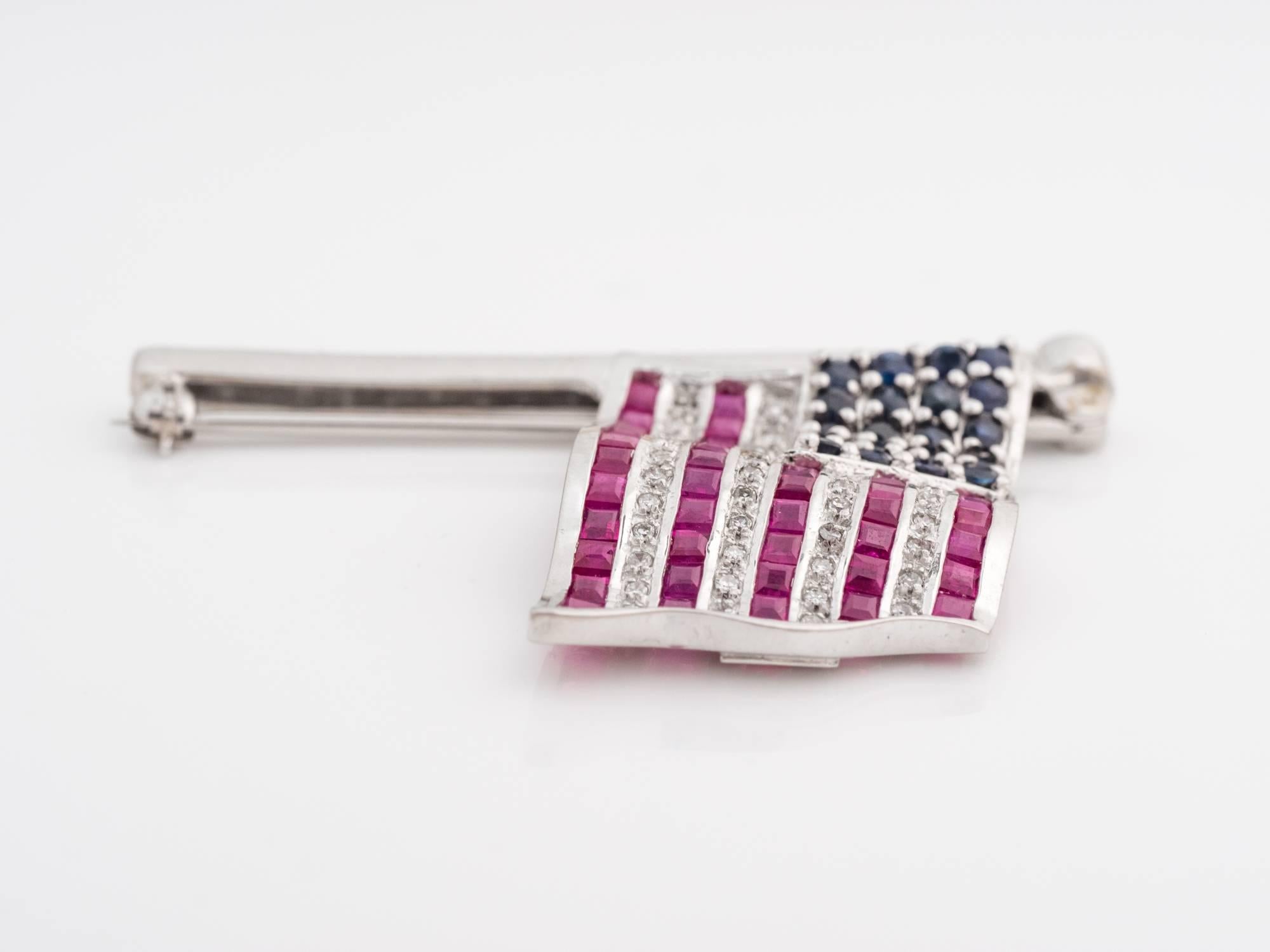 Hand-made American flag with natural round sapphires, natural square rubies and natural single cut diamonds. The 20 sapphires weigh .60 carats, 42 rubies weigh 2.00 carats, and the diamonds weigh .25 carats. The flag has hinges to allow a slight
