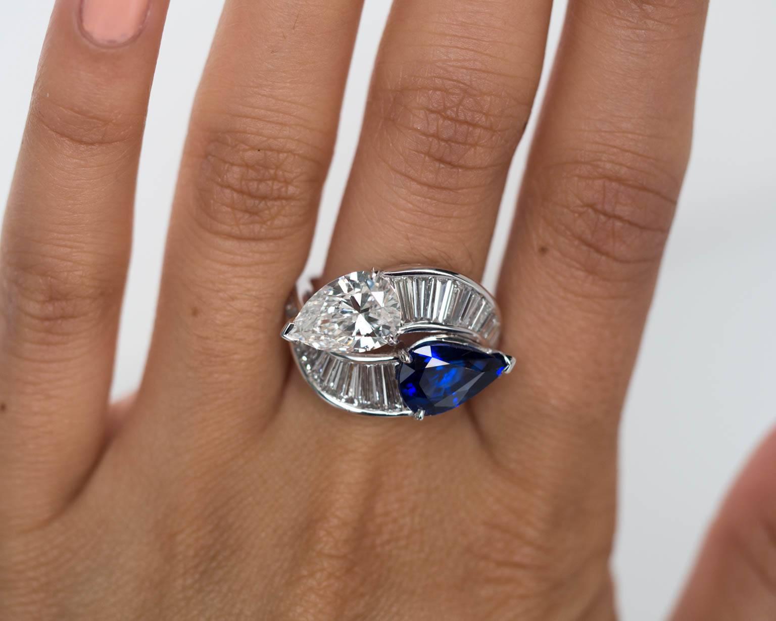 A true work of art. This cross-over ring features a GIA certified 2.15ct pear shape diamond at F-SI1 clarity as well as a 3.01ct royal blue sapphire with 
This piece is handcrafted in platinum, and there is metal engraving work around the entire