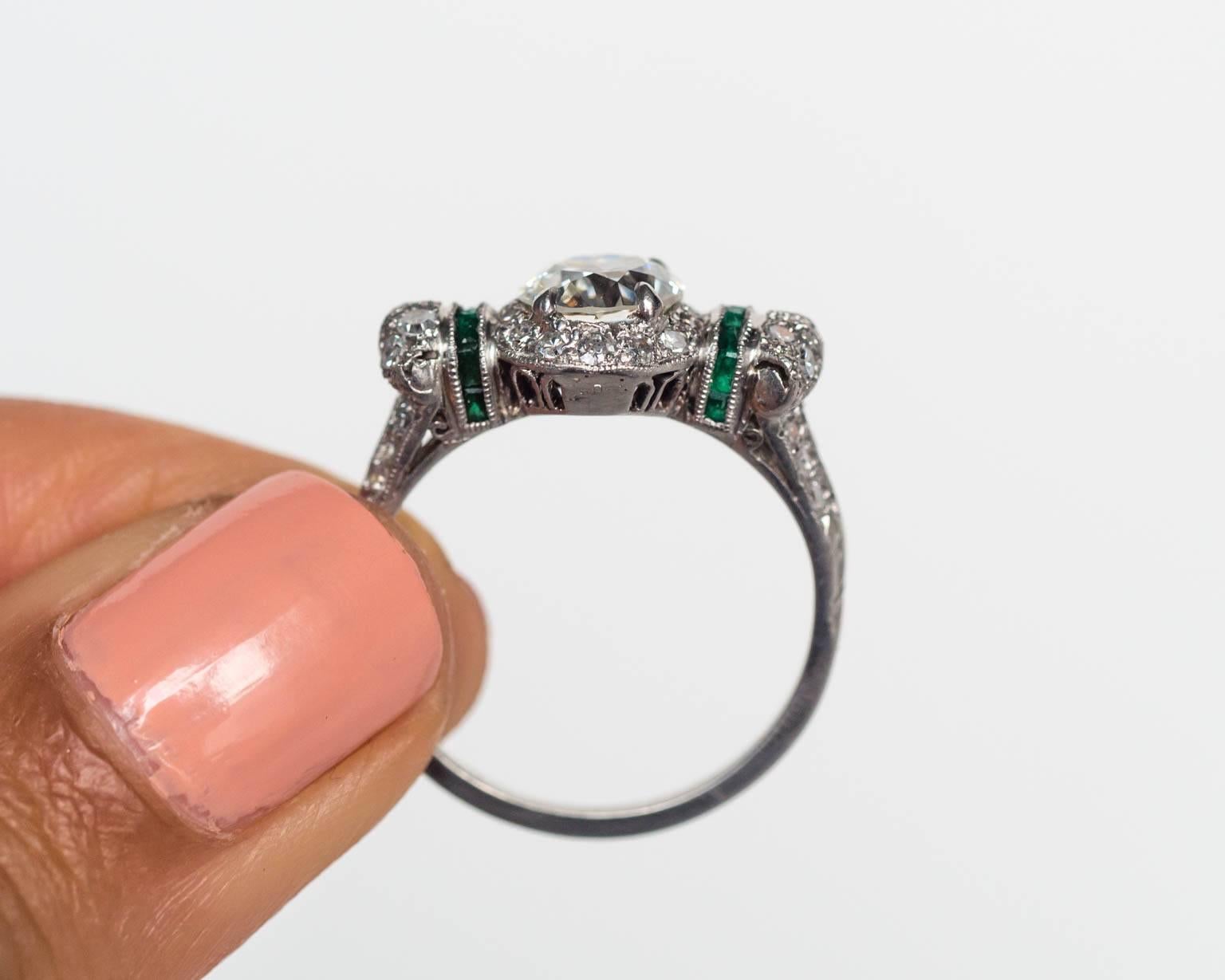 Spectacular and intricate Art Deco engagement ring. 

Center Diamond Details: GIA Certified. 
.97ct, I color, VS2 clarity. 
Report #2171876537

Metal: Platinum
Emerald Details: Natural, .25cttw, Pure green. 
Ring Size: 6.5

This ring can