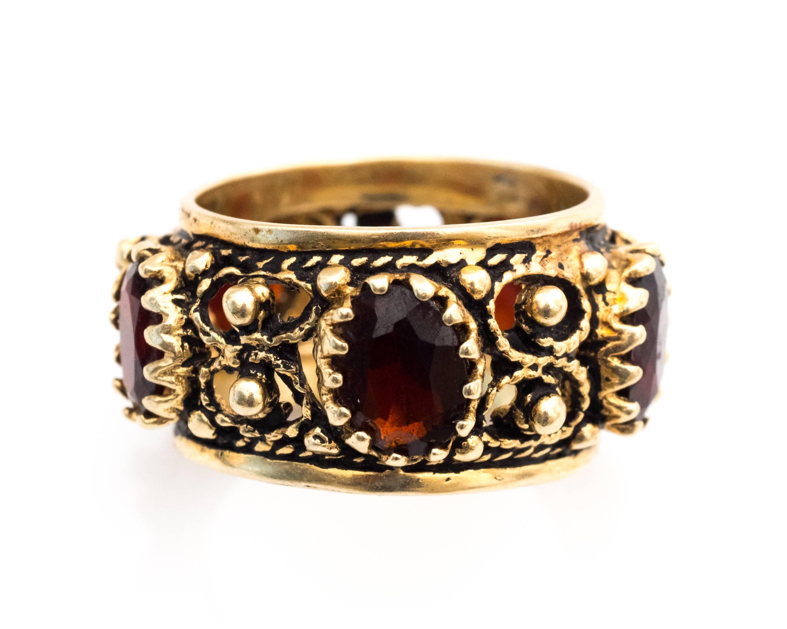 Beautifully crafted 14 Karat Yellow Gold and Garnet Cigar Band

Features 5 Garnet Stones, Oval Cut, each stone measures 7 millimeter x 6 millimeter, with a total of 2.5 carats. 

Intricate carvings and detailing on the design (Repetitive) throughout