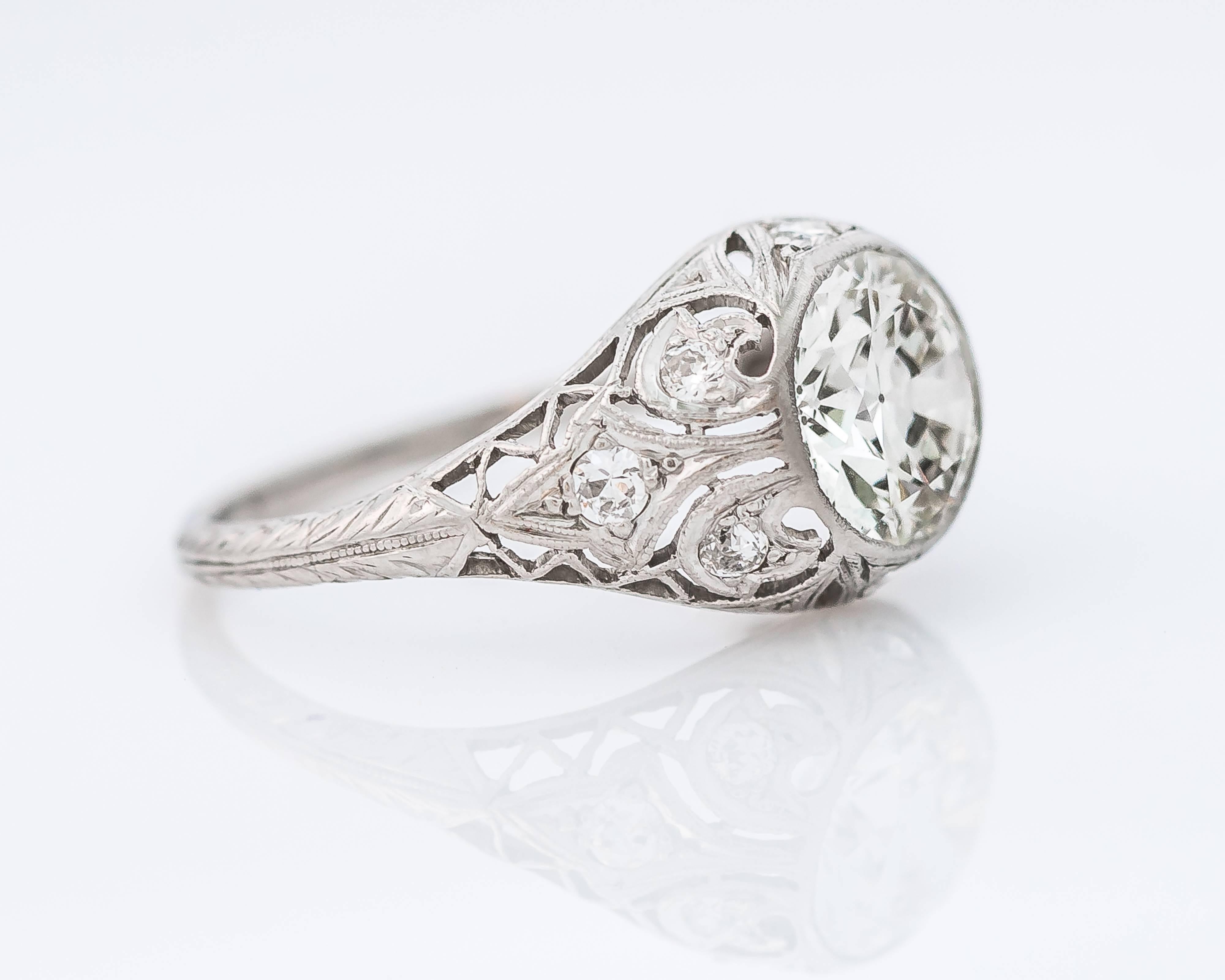This stunning, timeless 1925 antique art deco engagement ring features a 2.85 carat Old European cut center stone bezel set in a delicate filigree platinum. The gallery work and etching through the shank is a beautiful add-on to this ring, giving it