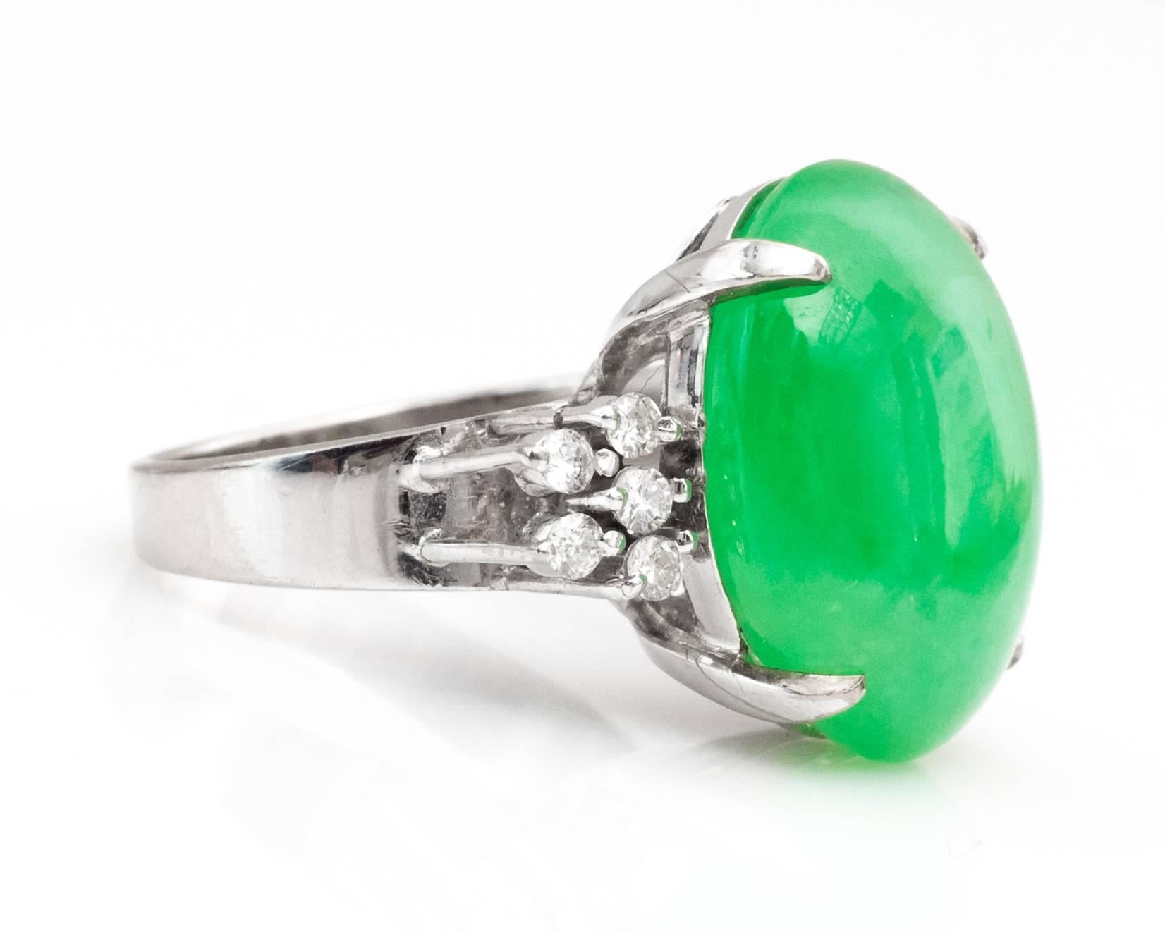 Gorgeous Jade Ring from the 1960s. 
Features an ornate size oval cut jade with accent sparkling diamonds on either side of the ring. Diamonds and Jade are all prong-set. The ring is crafted in 14 karat white gold. Hallmarked 585 on the inside of the