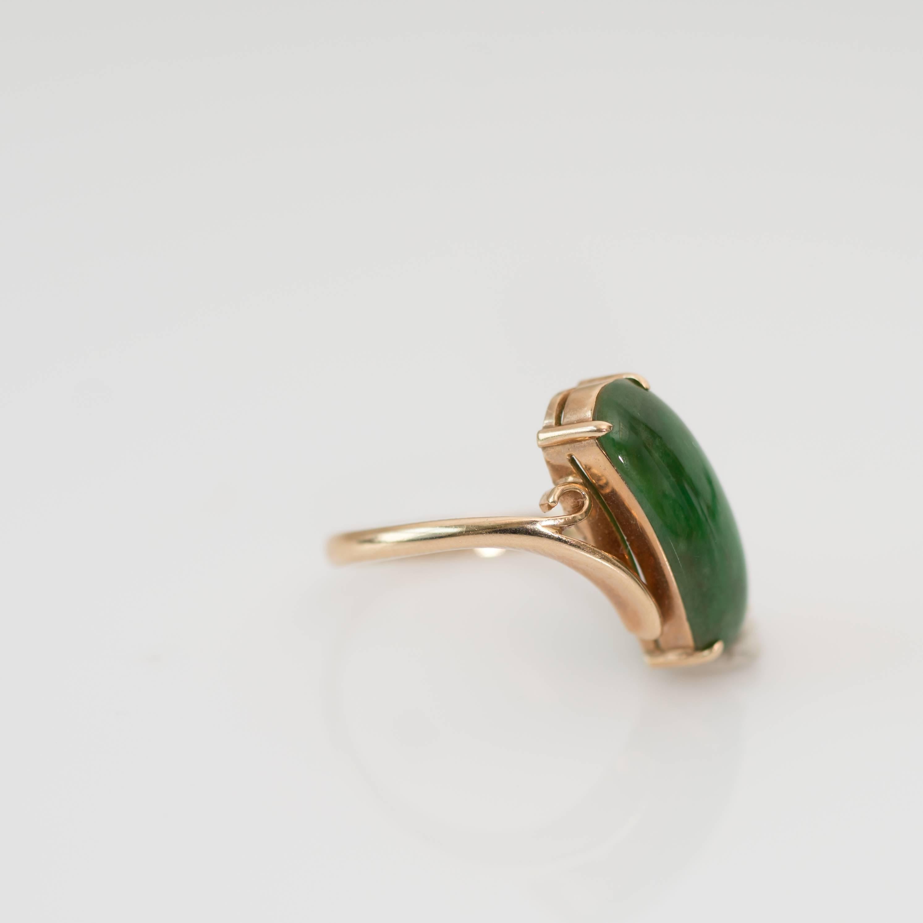 This elegant elongated Jade Cabochon ring came to us from a Hong Kong estate. It sits diagonally on the finger creating a slimming and lengthening effect. 

The 14 karat yellow gold perfectly accents the medium to dark green prong set Jade center