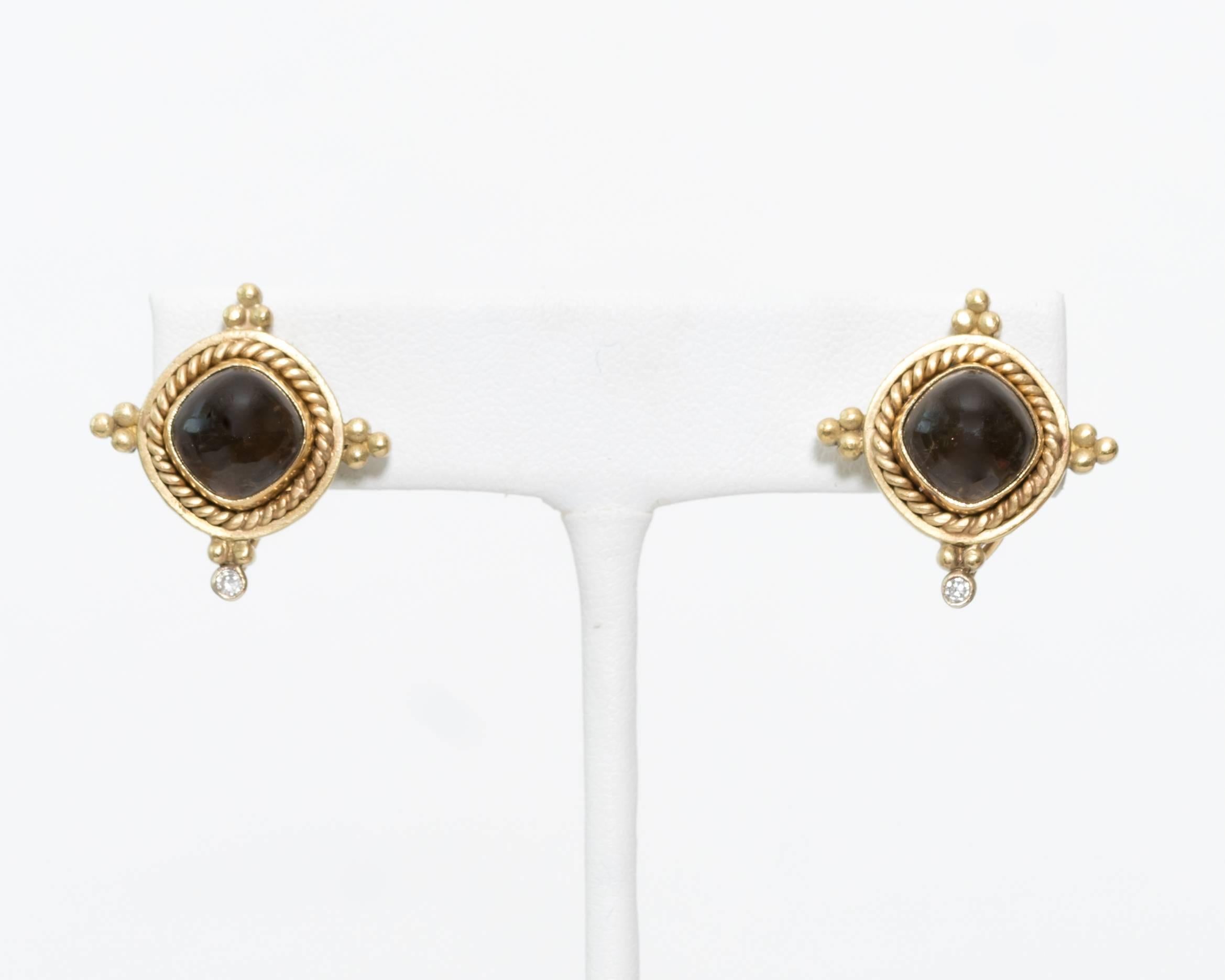 You will want to wear these classically beautiful earrings everywhere! They feature a 9 millimeter smoky quartz center stone set in 18 karat yellow gold with an accent diamond drop at the bottom of each earring. 

A gold rope motif frames each smoky
