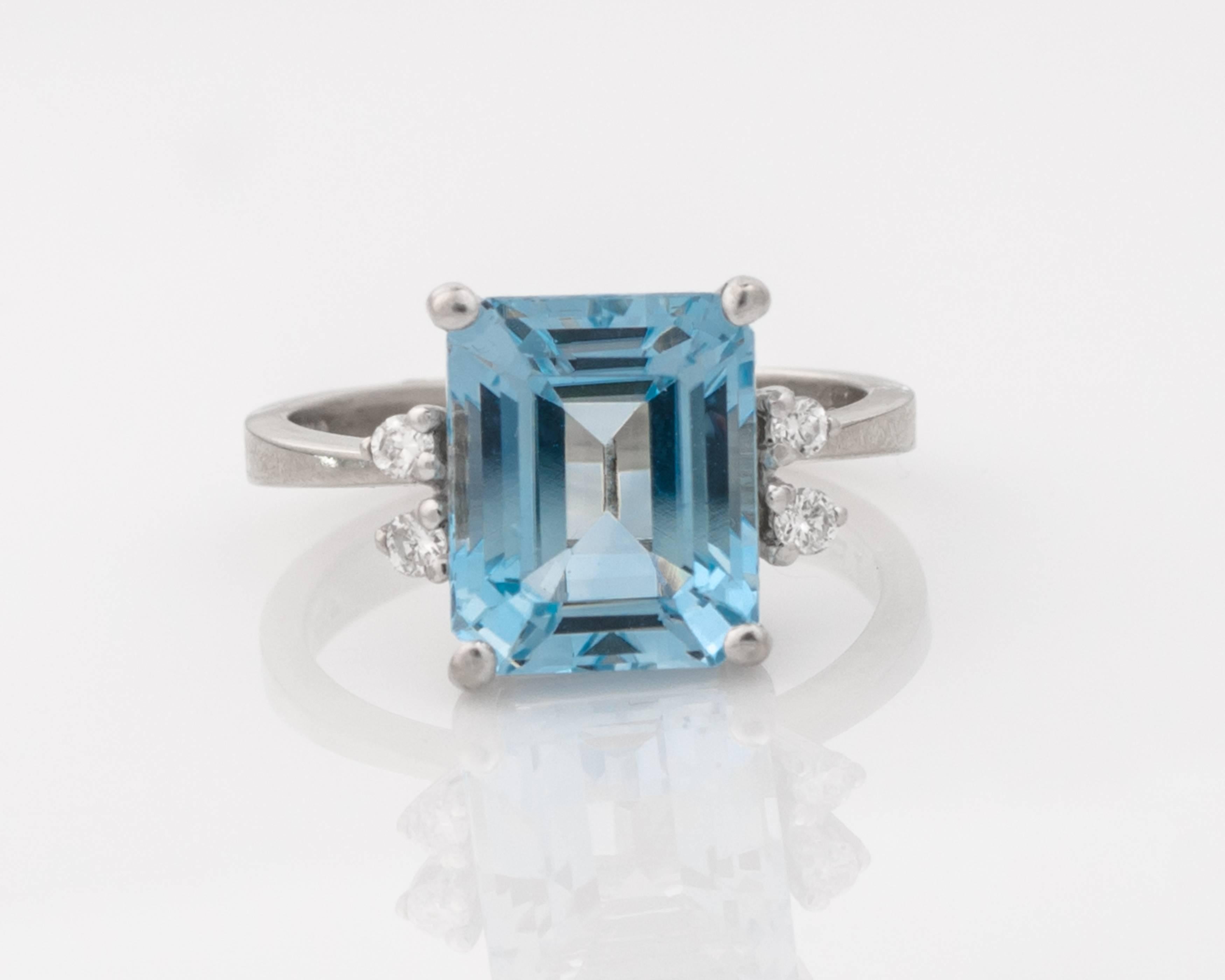 This 1980s Aquamarine and 14 Karat White Gold ring features a 5 carat Aquamarine accented by 4 round brilliant diamonds totaling 0.12 carats total weight. The aquamarine is held with four prongs in a high cathedral setting. The diamonds are also