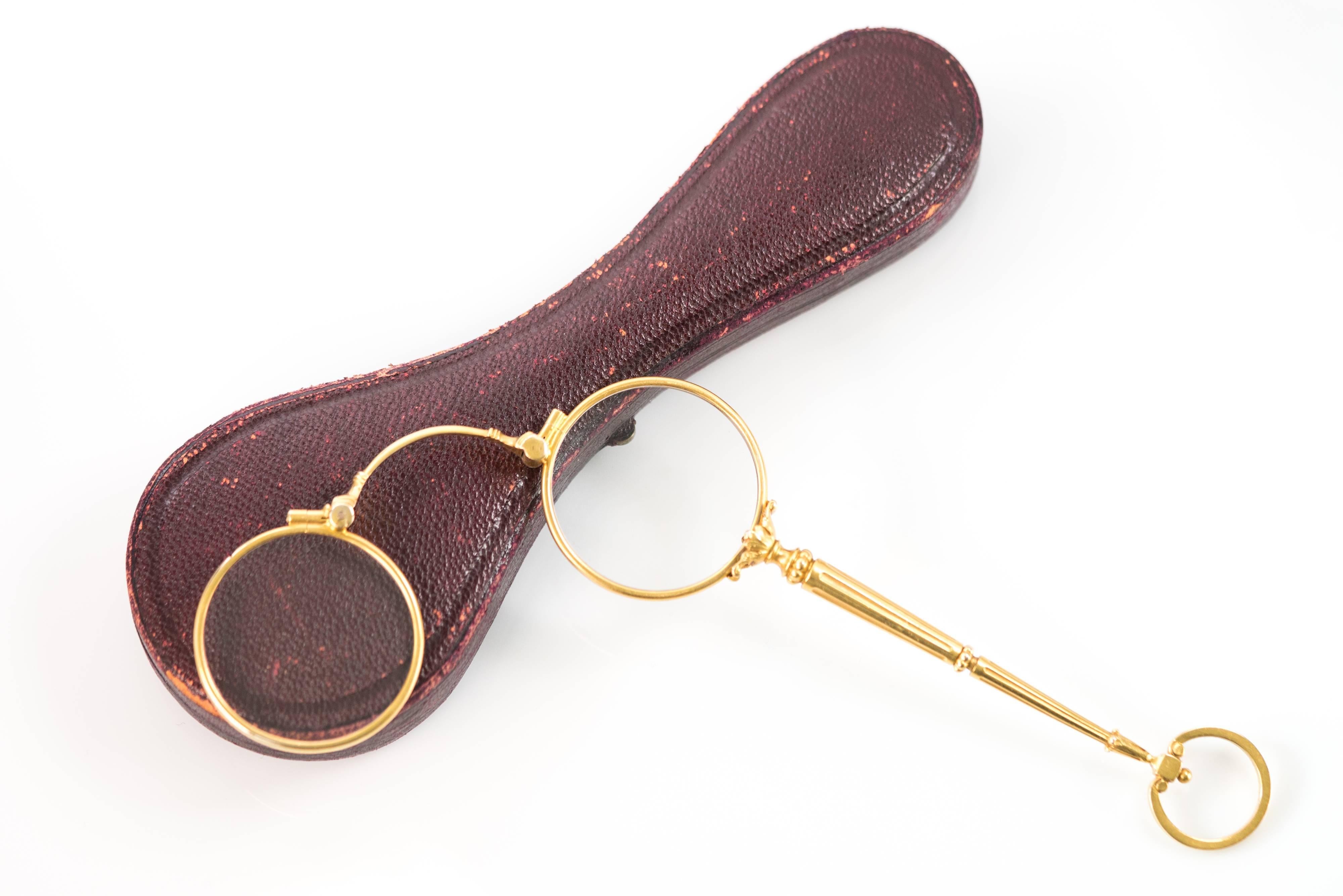 This turn-of-the-century pair of 14K Yellow Gold Curry and Paxton London Bifocal Lorgnette Spectacles comes in the original burgundy leather and purple velvet, hinged, locking case. A delicate and decorative pull lever in the center of the handle