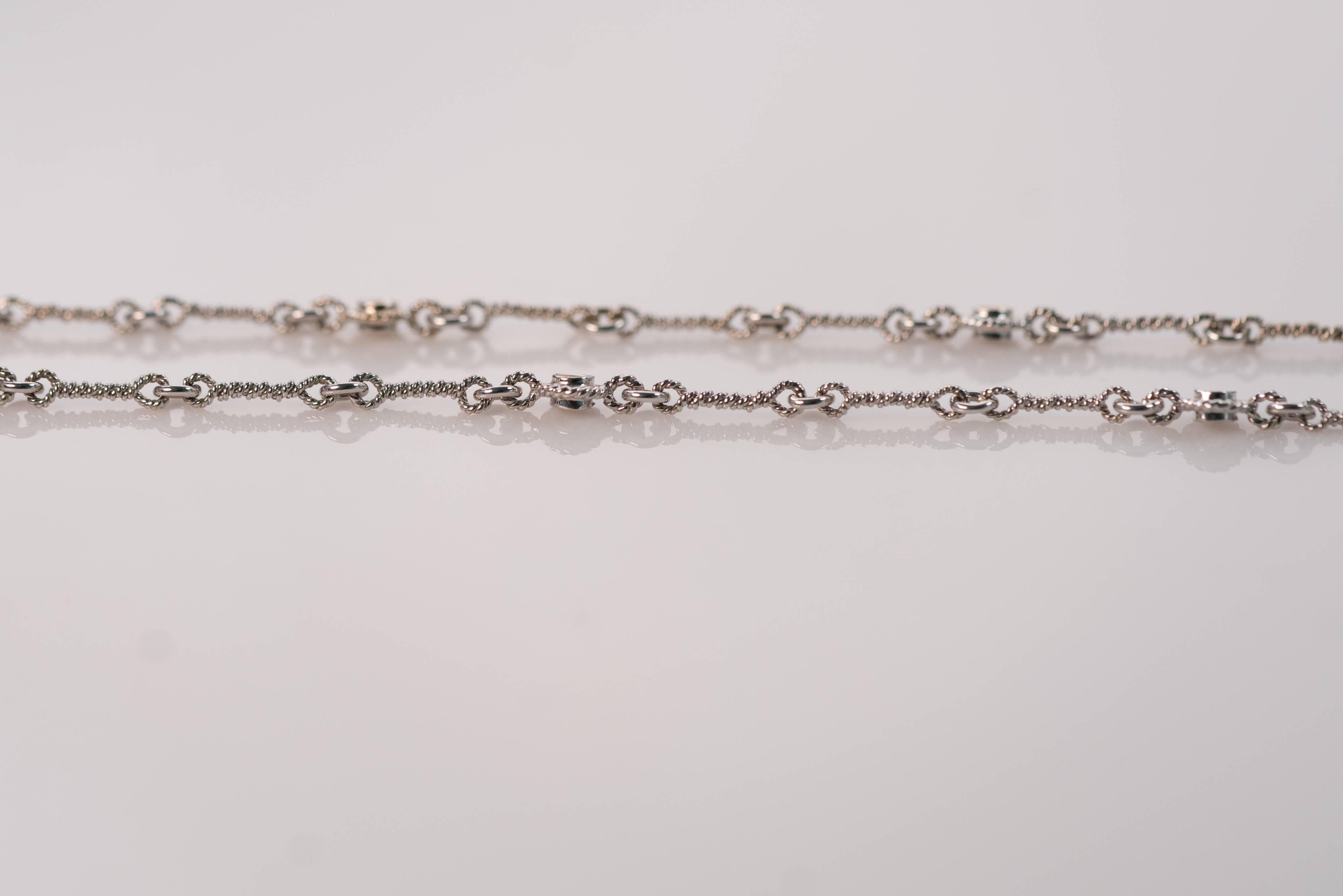 The wire-turned links of this 1990s 18 karat white gold and diamond necklace give classic simplicity a modern decorative twist. 
Made in Italy, this necklace features a lobster claw clasp and eight bezel set diamonds evenly spaced with wire-turned