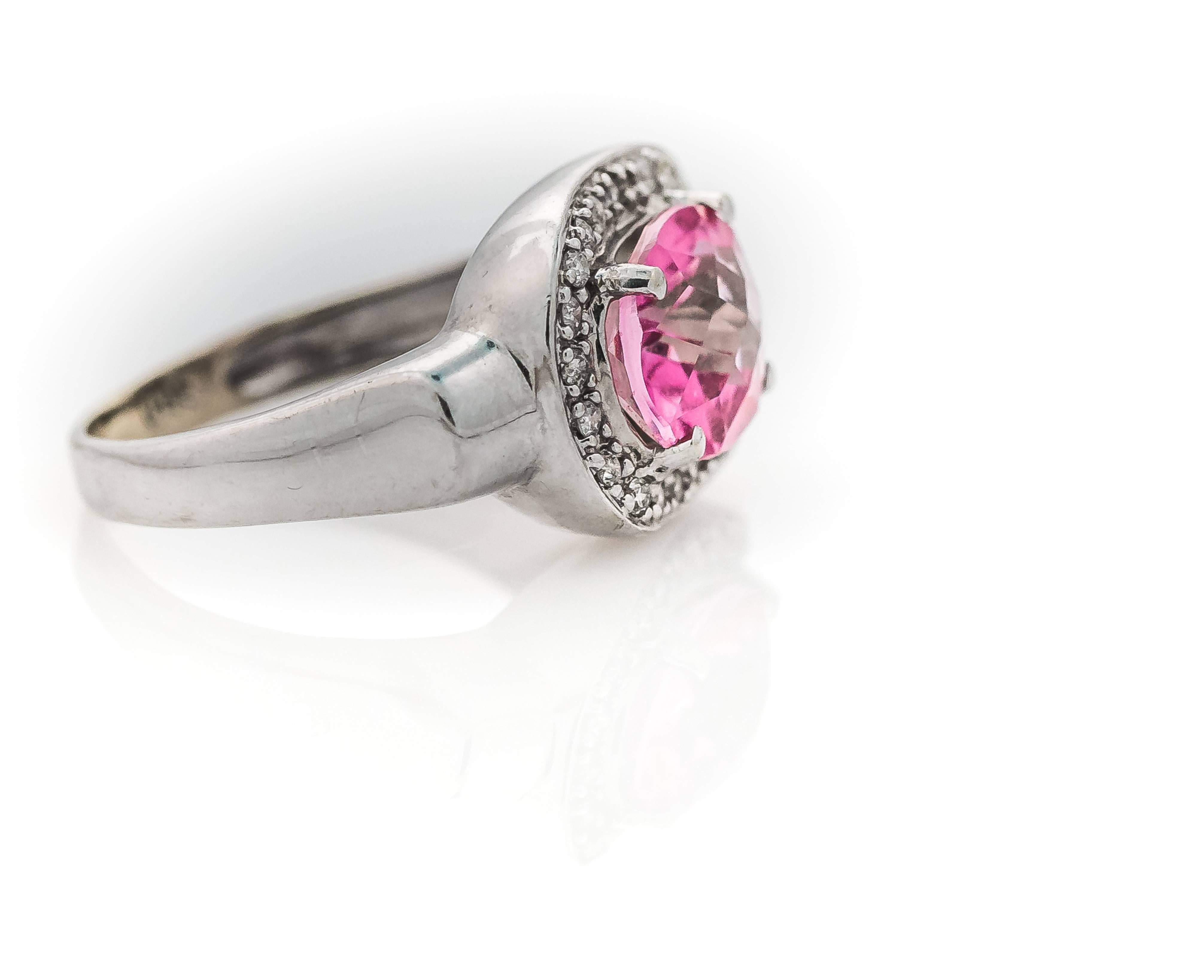 You'll love this angelic 1980s 3 carat Pink Topaz and Diamond Halo 14 karat white gold cocktail Ring. 

Diamonds featured here weigh 0.25 carats total weight, all prong set.
The diamonds surround an oval prong set Pink Topaz weighing a whopping 3