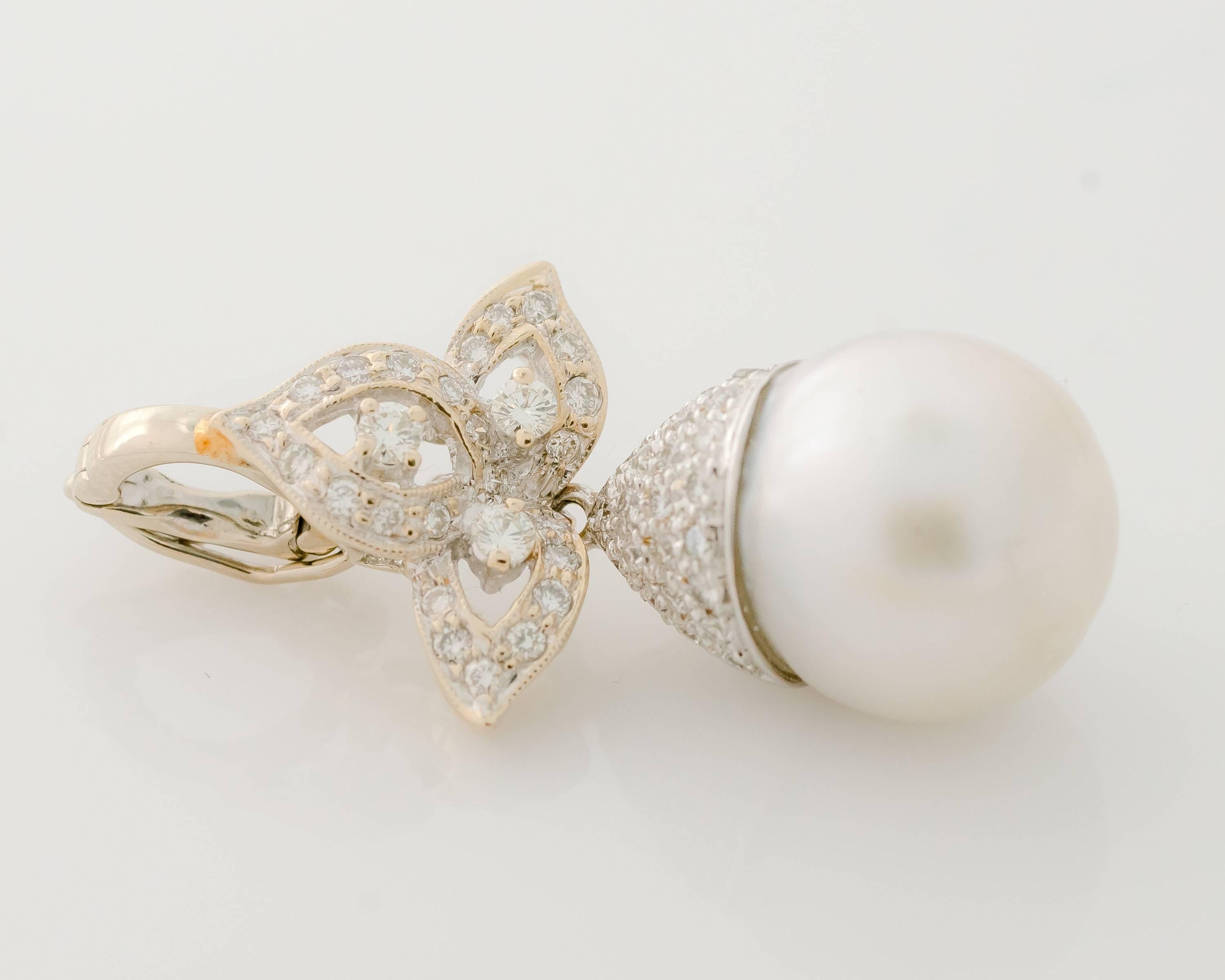This 1980s Diamond and Pearl Pendant features a 13.5 millimeter grayish-white pearl topped with sparkling round brilliant diamonds set in 14 karat white gold. The articulated pendant features a leaf-motif, diamond encrusted upper half which has a