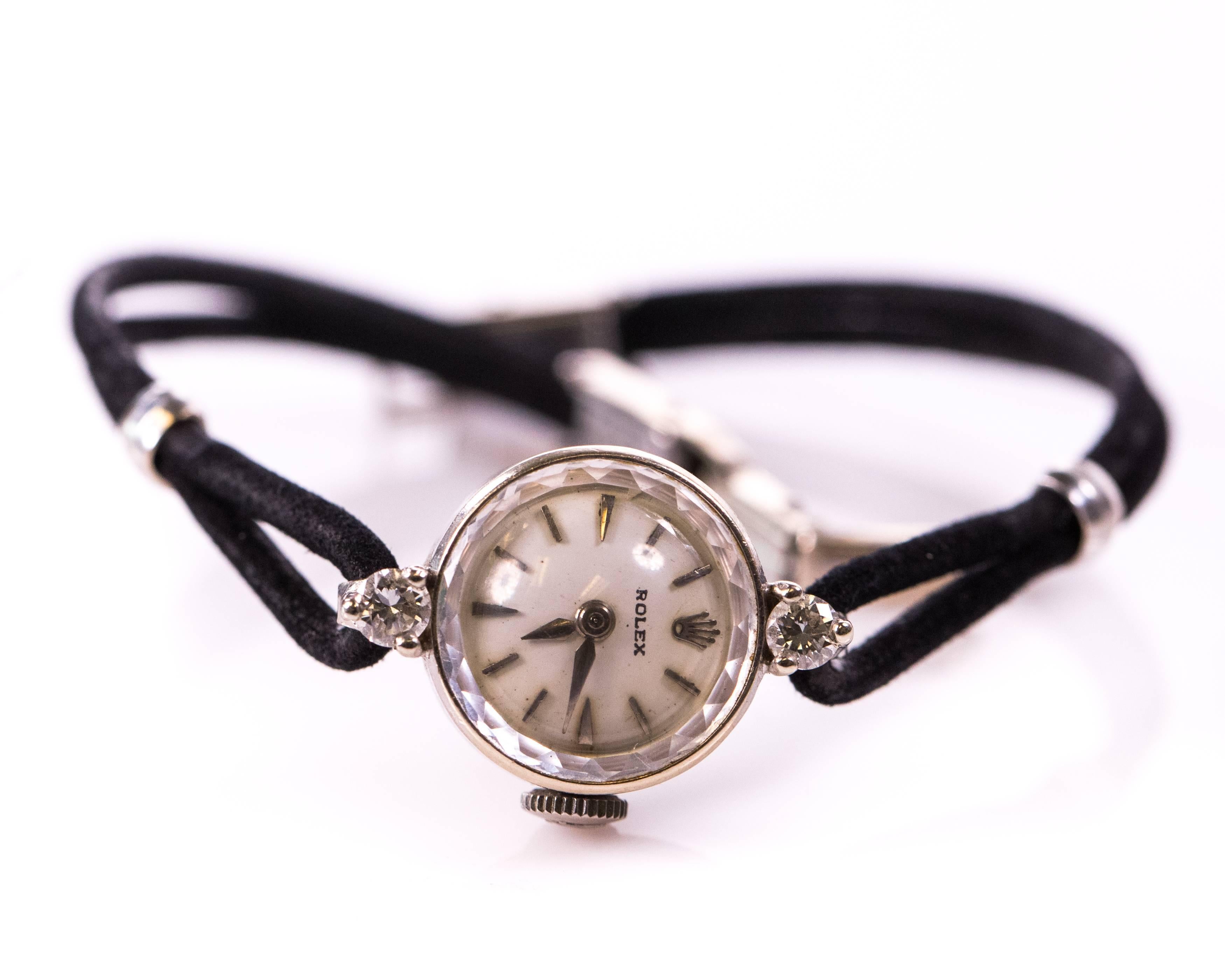 This 1940s Retro Rolex Diamond and 14K White Gold ladies watch features a .20 carat round brilliant diamond at the 12:00 and 6:00 positions. The black satin cord custom bracelet has a secure locking clasp and will fit up to a 7.5 inch wrist. In true