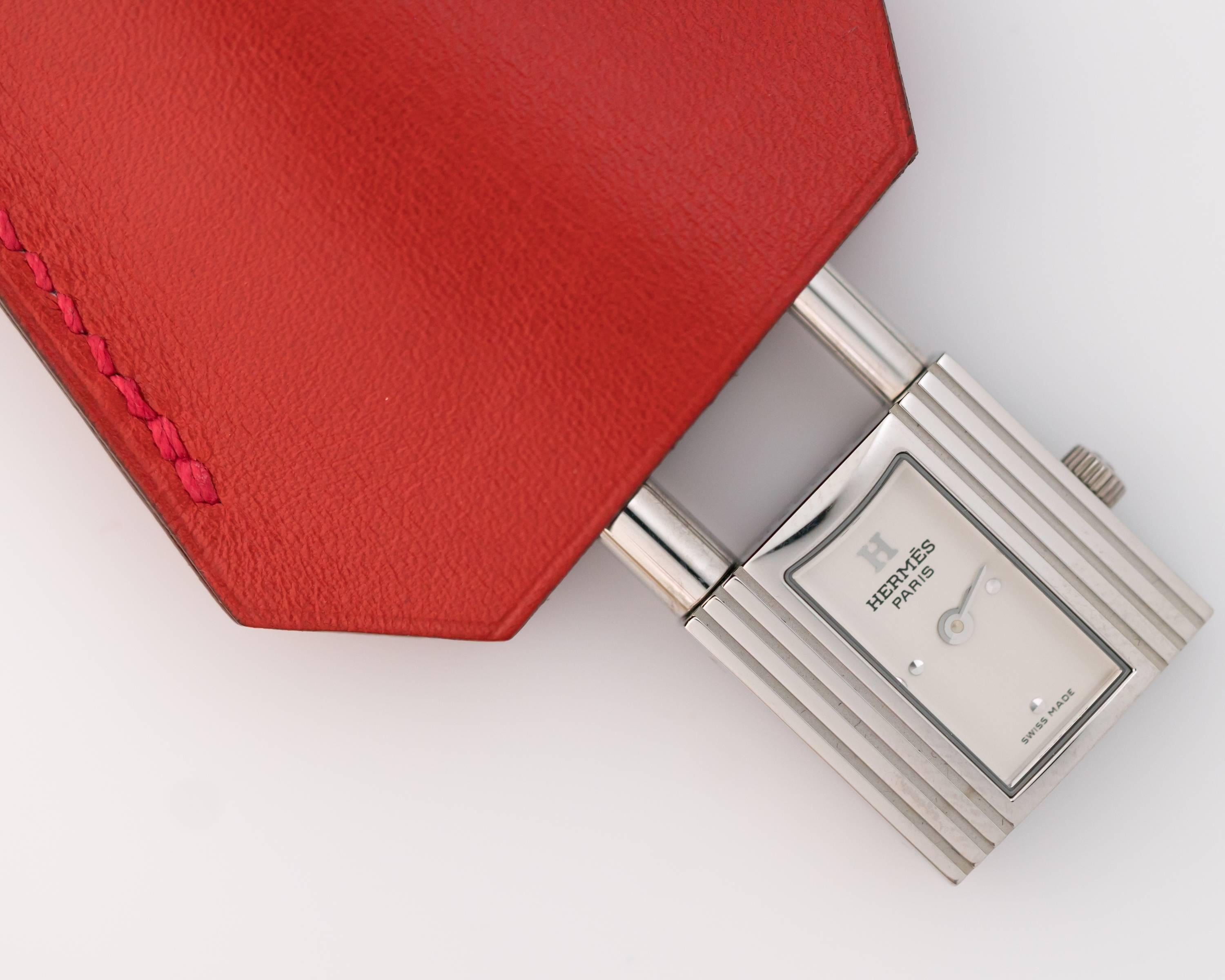 Hermes Paris Stainless Steel Kelly Watch, Iconic Designer! 
Brand New in the Original Box - this is the perfect accessory for your purse. This lock motif watch attaches to a red leather strap and retracts into the protective red leather cover. This