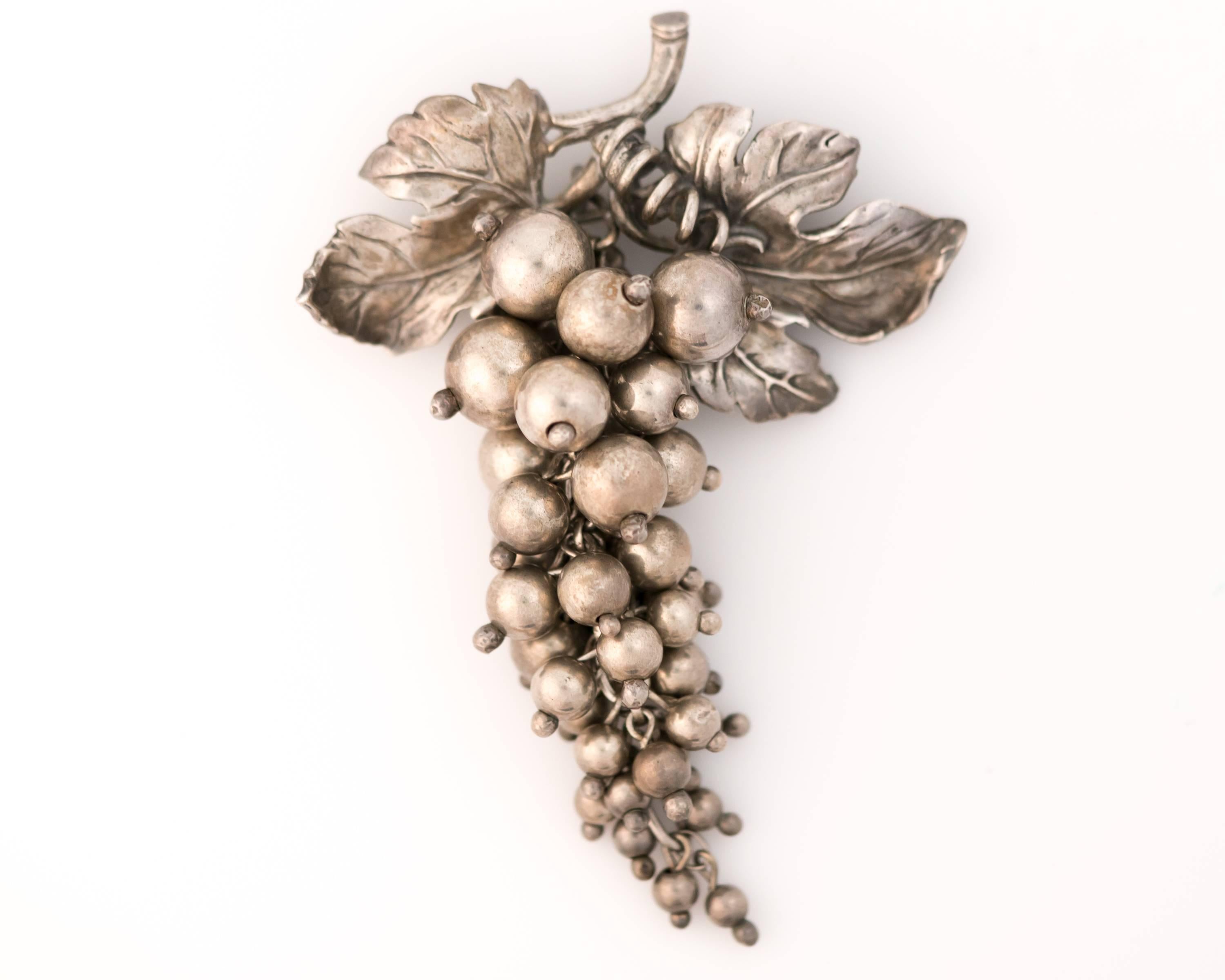 This Highly Collectible 1960s Retro Sterling Silver Brooch is gorgeous and fun! 
It features a cluster of silver grapes in varying sizes graduated from larger to smaller and from top to bottom. Each silver grape is attached to a central chain which