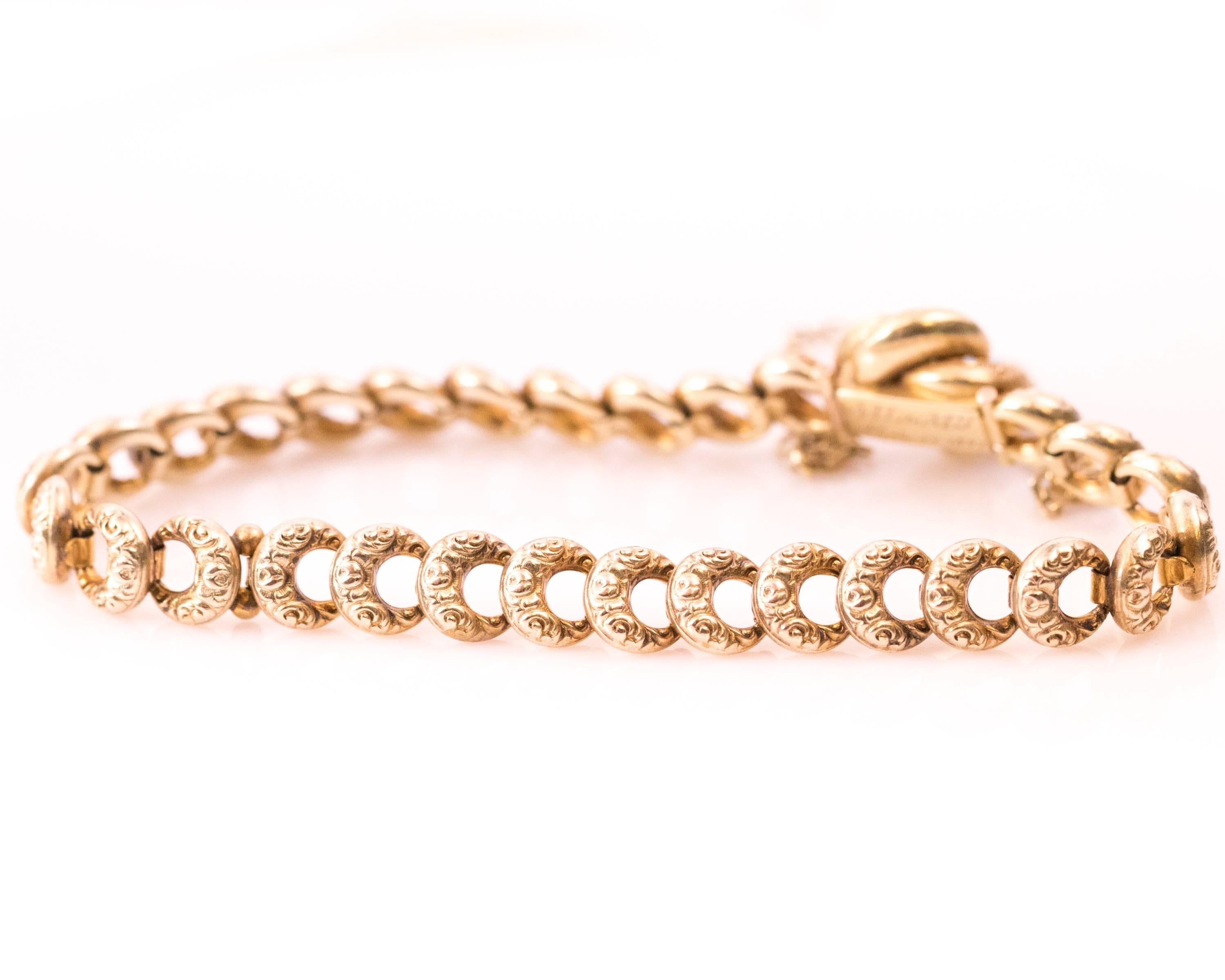 This 1897 Victorian Old Mine Diamond and 14K Yellow Gold Crescent Link Bracelet features Victorian Enamel details. The crescent link chain comes together at the flower knot clasp. The center of the clasp has .03 carat Old Mine round solitaire