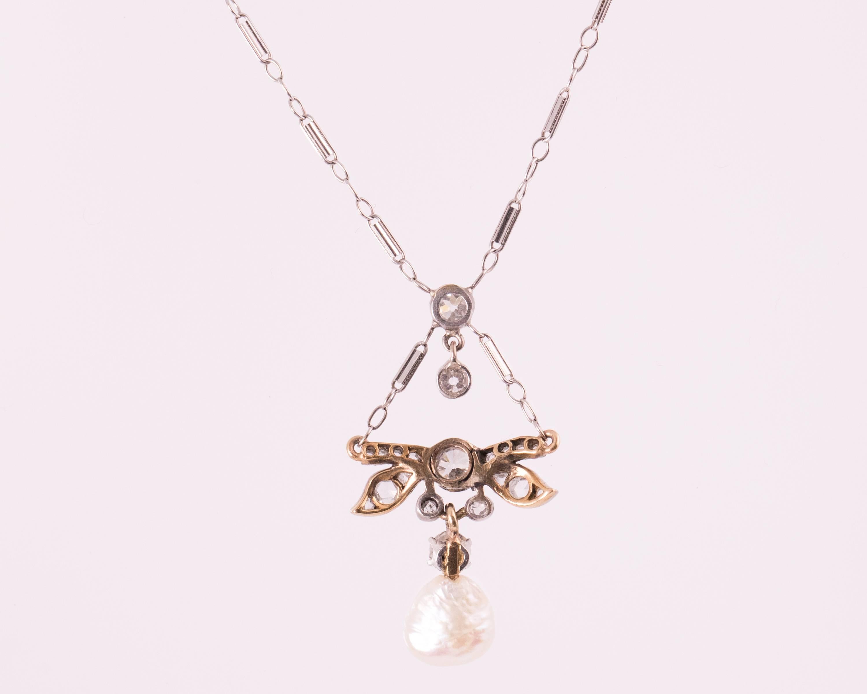 This 1870s Victorian Dragonfly motif Necklace features a Natural Free Form Pearl and Old Mine Diamonds in 14 Karat White Gold and Platinum. A Diamond Dragonfly charm drops from the chain and suspends a diamond and pearl charm. The Natural Pearl