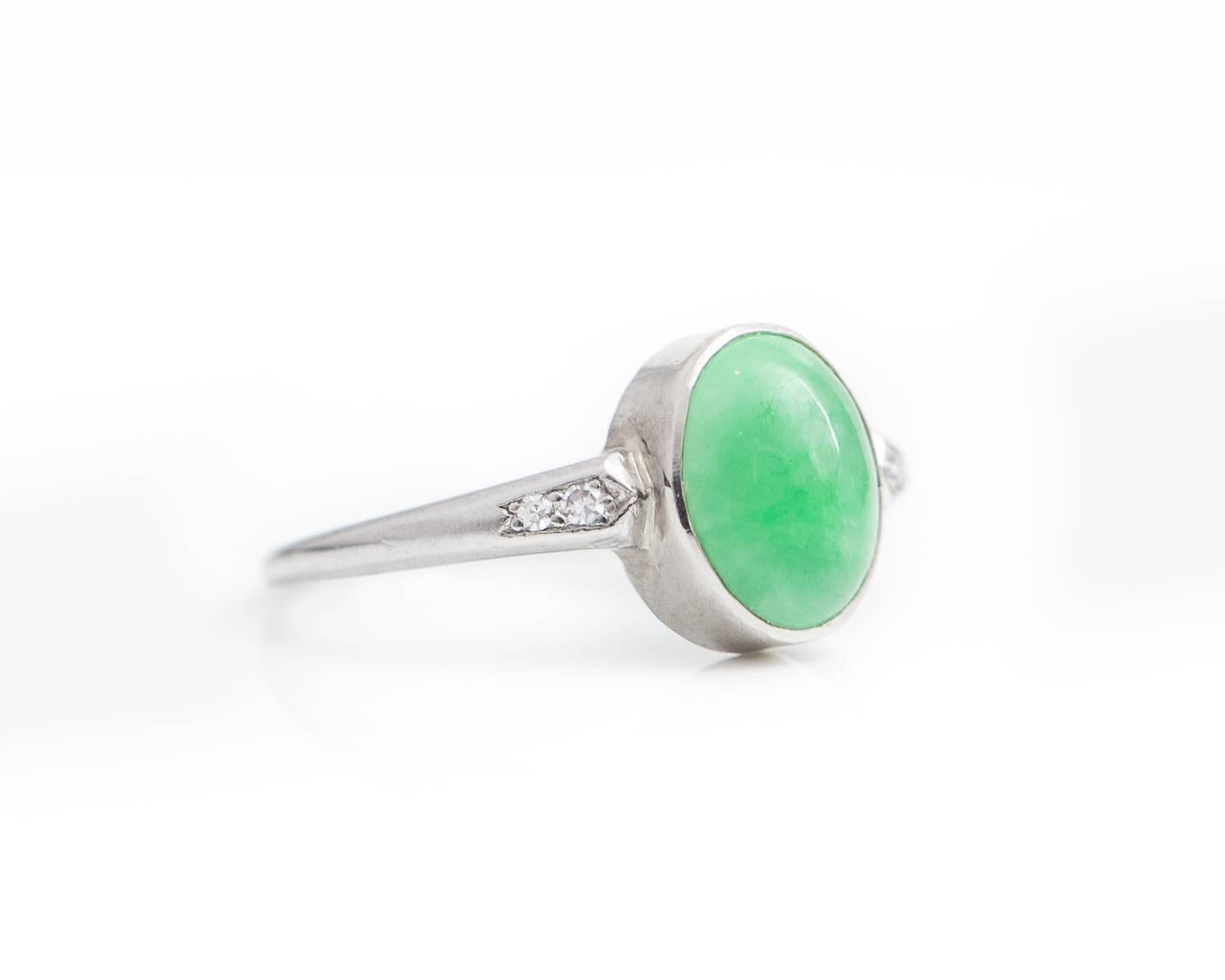 1930s Art Deco Oval Jade Cabochon with Diamond and Platinum Ring. Features a bezel set 1.0 carat Oval Jade Cabochon with 2 prong set Single Cut Round Diamonds on each side. The Candy Apple Green Jade Cabochon has minor, naturally occurring