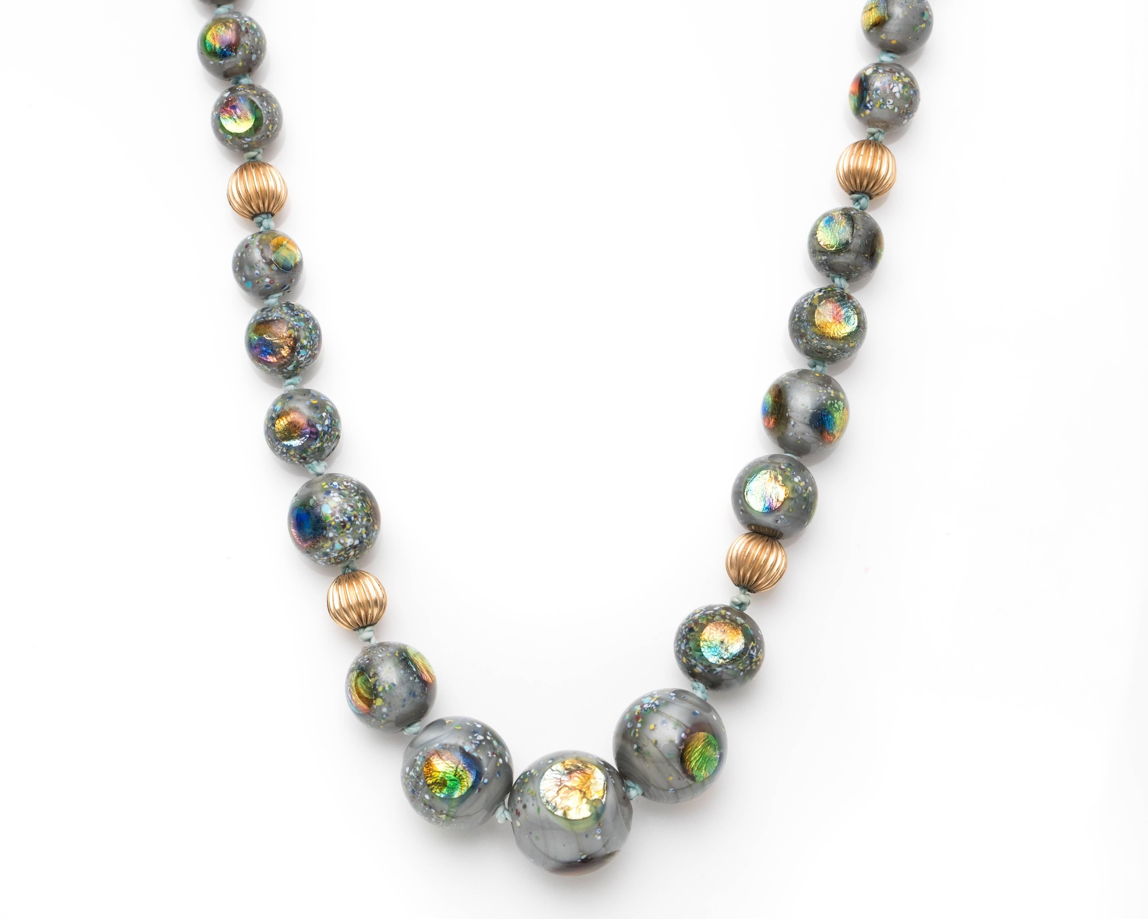 1960s Retro Ammolite Inlaid Glass and 14 Karat Yellow Gold Bead Necklace. Features Glass Beads in graduated diameters from 6.4 millimeters to 16 millimeters. Each glass bead is Inlaid with colorful, iridescent Ammolite. The Ammolite adds a rainbow