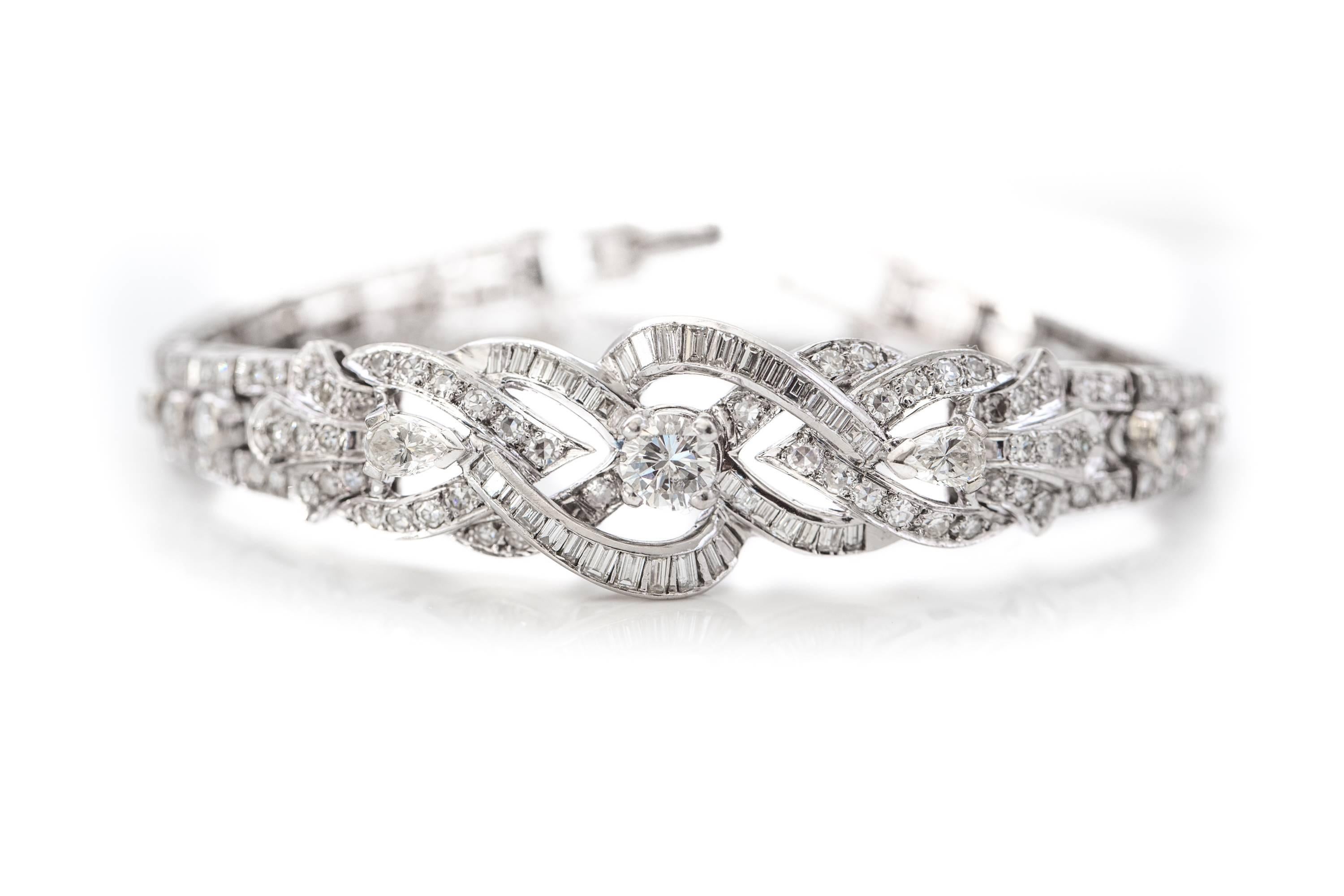 1950s Retro Diamond and 14K White Gold Bracelet. The primary section features a .65 carat Center Diamond set atop the center of an infinity shape set with baguette and round diamonds. A baguette-set half-heart sits to the upper left and lower right