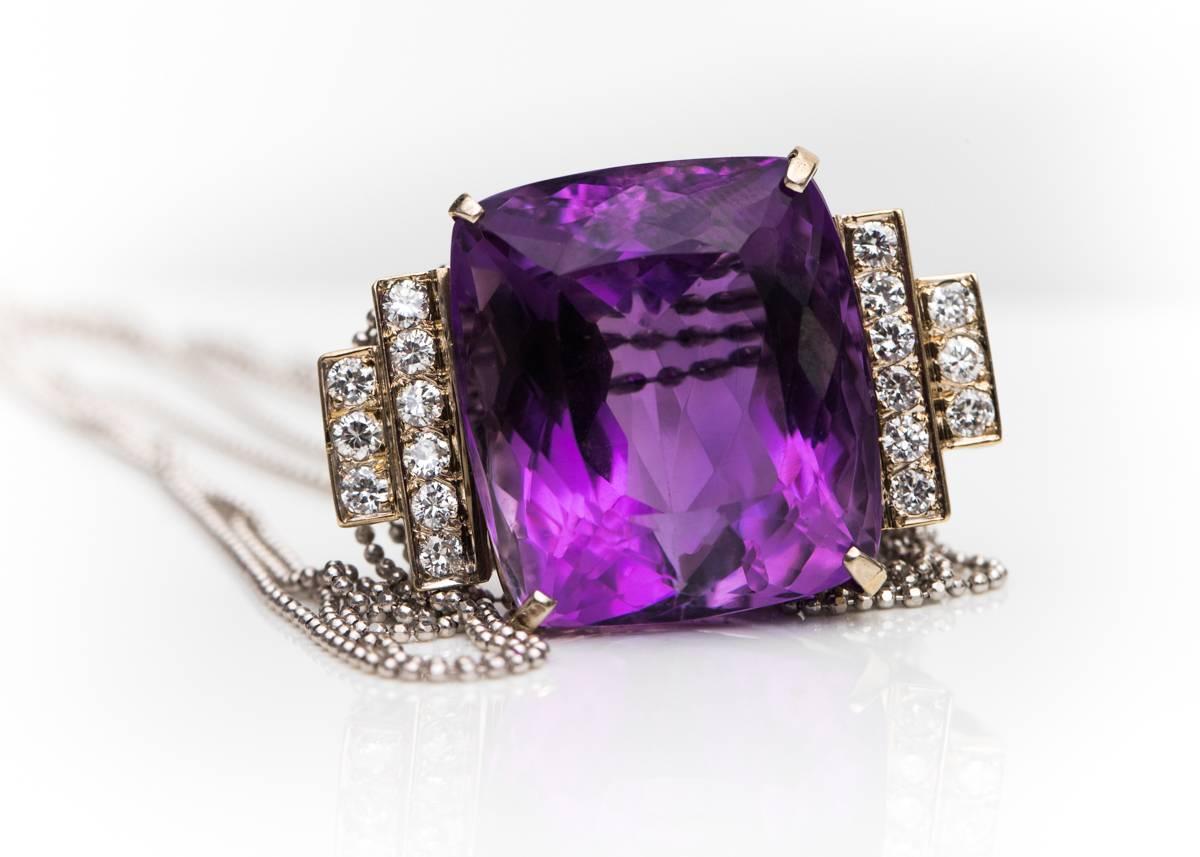 1950s Retro 20 Carat Amethyst, Diamond and 14 Karat White Gold Necklace.

Features a 20 Carat Amethyst flanked by 18 Round Brilliant Diamonds. The cushion cut Amethyst is flanked by 2 vertical rows of diamonds on each side. The first row holds 6