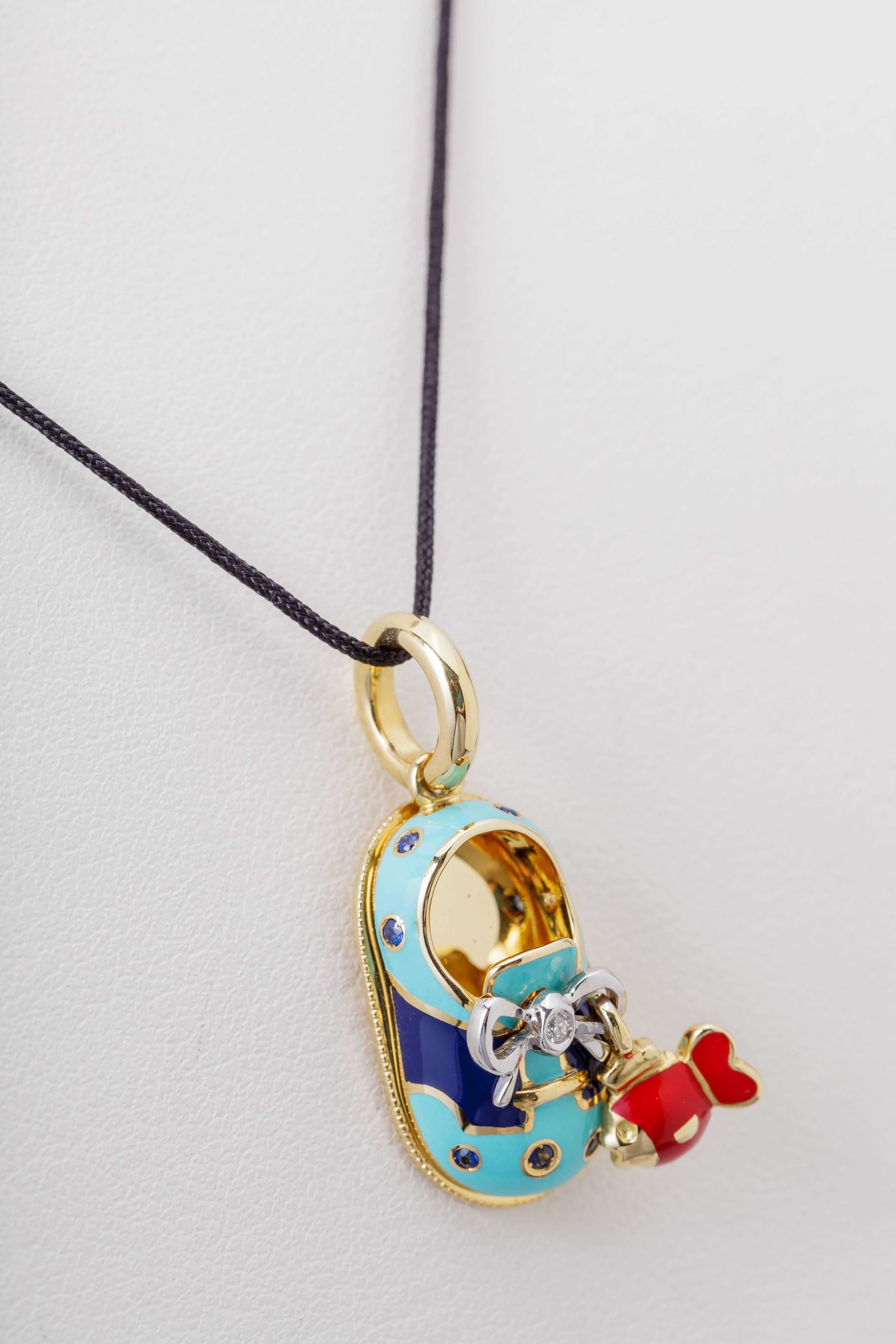 This Aaron Basha charm features a blue shoe with a red fish hanging on the shoelace.  The charm is 18k yellow gold with enamel and is set with a single 0.01ct diamond.