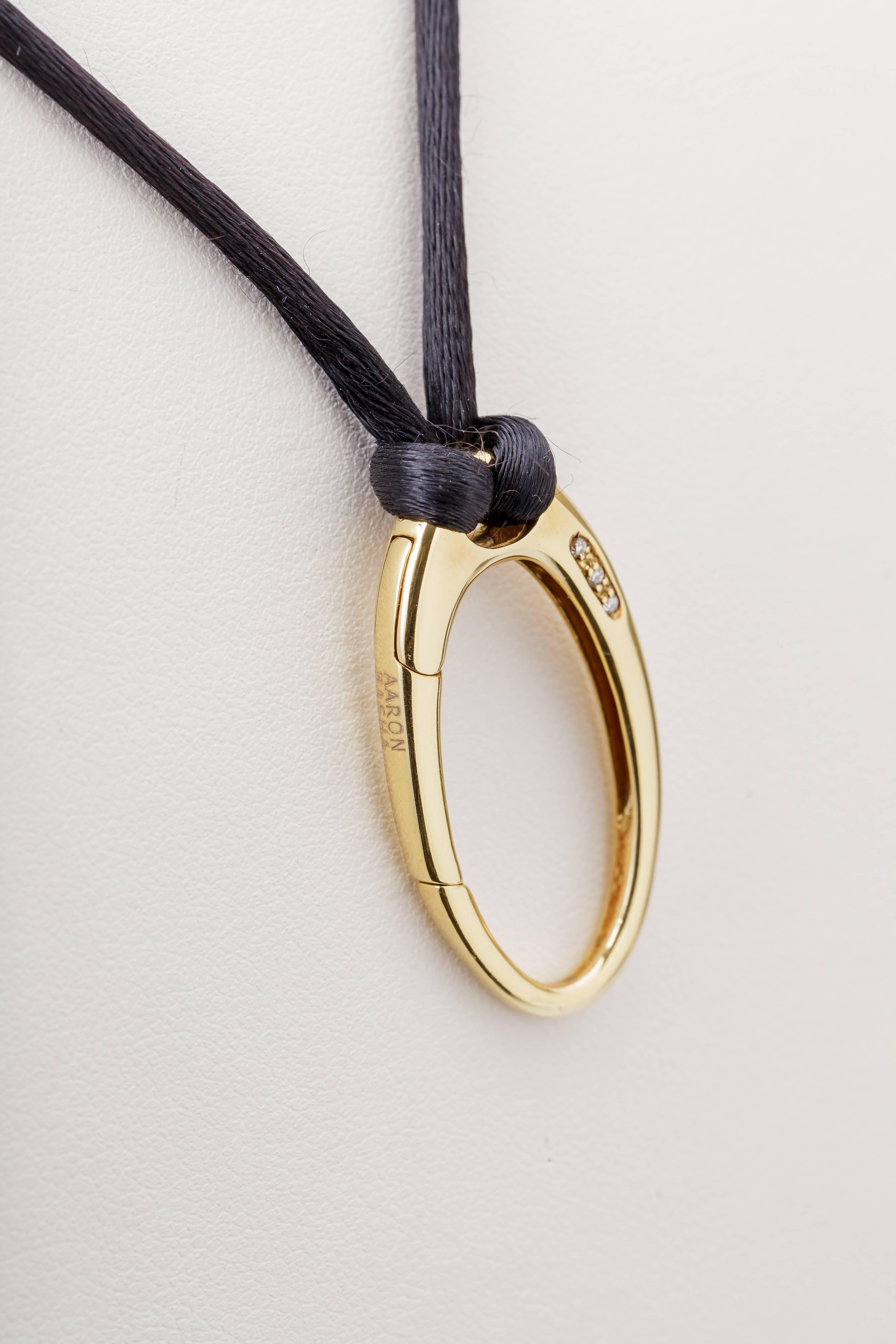 This Aaron Basha oval pendant clasp is 18k yellow gold and is set with three diamonds totaling 0.04ct.  It is on a black cord with an 18k lobster clasp.