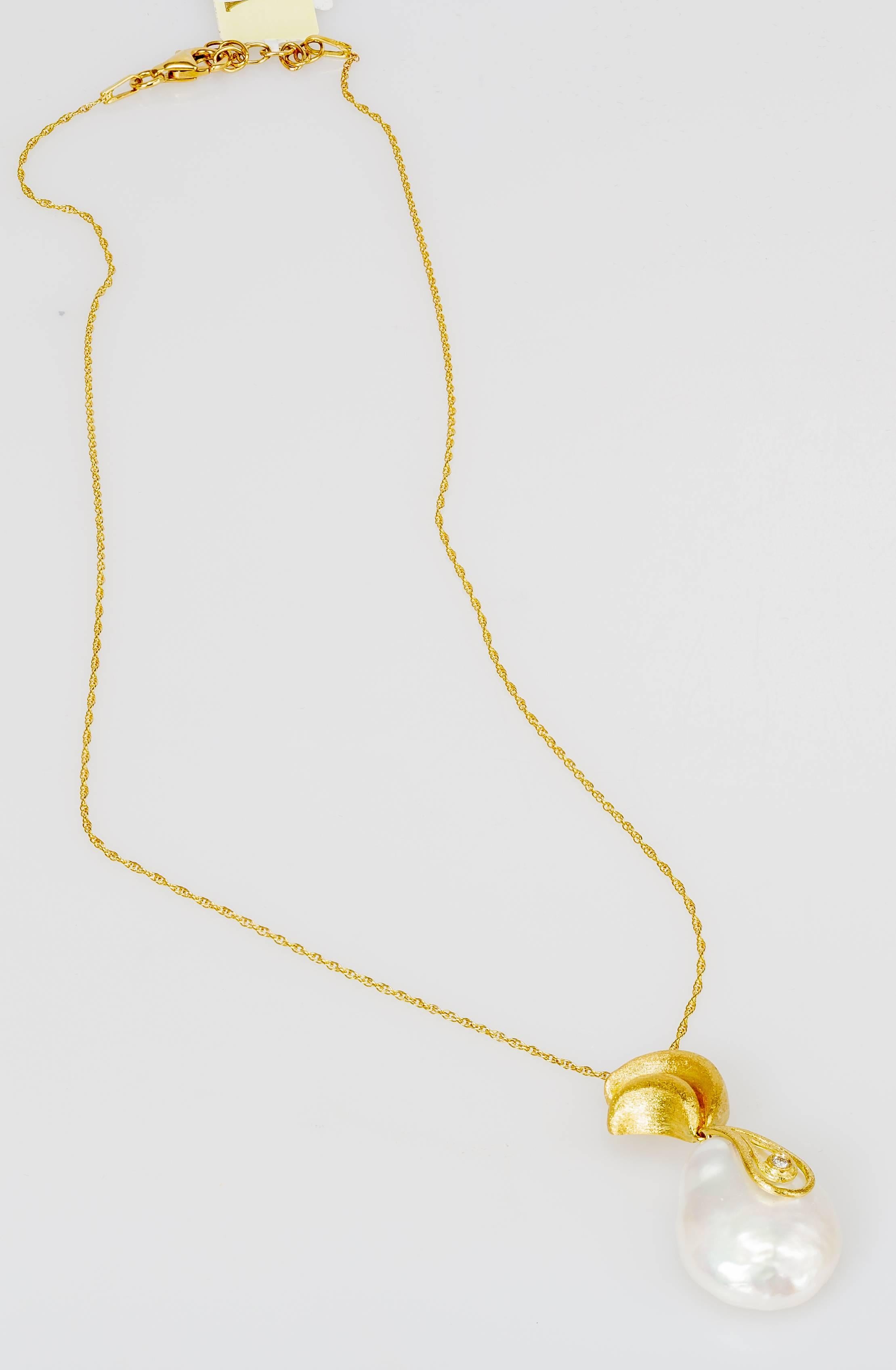 This 18k yellow gold Yvel necklace features a white Baroque pearl on an 18k yellow gold pendant set with a 0.01ct diamond.  The chain measures 16 inches long.