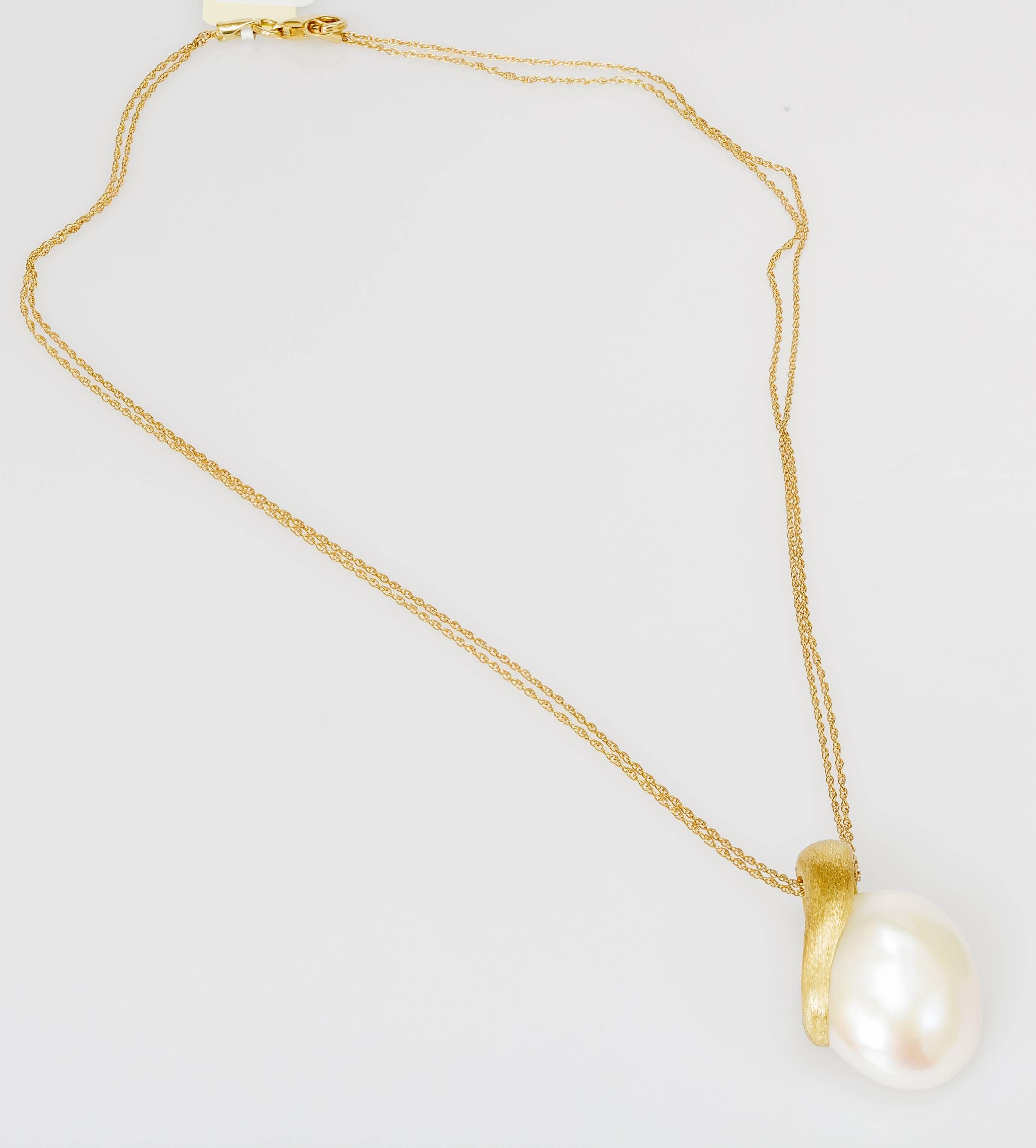 This Yvel necklace features a baroque pearl and satin brushed 18k yellow gold pendant on a 16 inch 18k yellow gold chain.