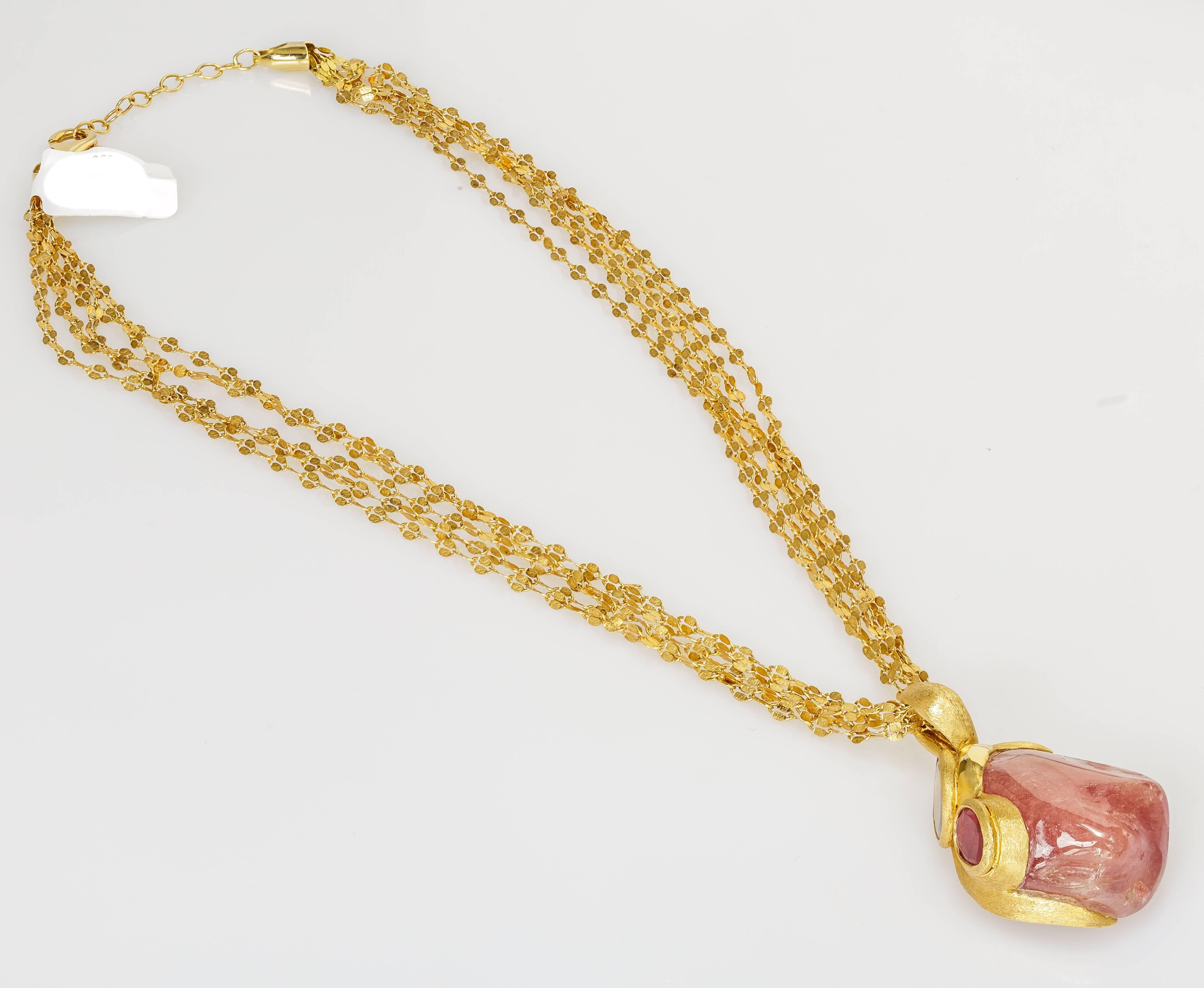 This Yvel necklace features a tumbled natural reddish pink fancy colored sapphire on an 18k yellow gold pendant with two smaller sapphires.  The pendant hangs from an 18 inch 18k yellow gold multi-strand chain.