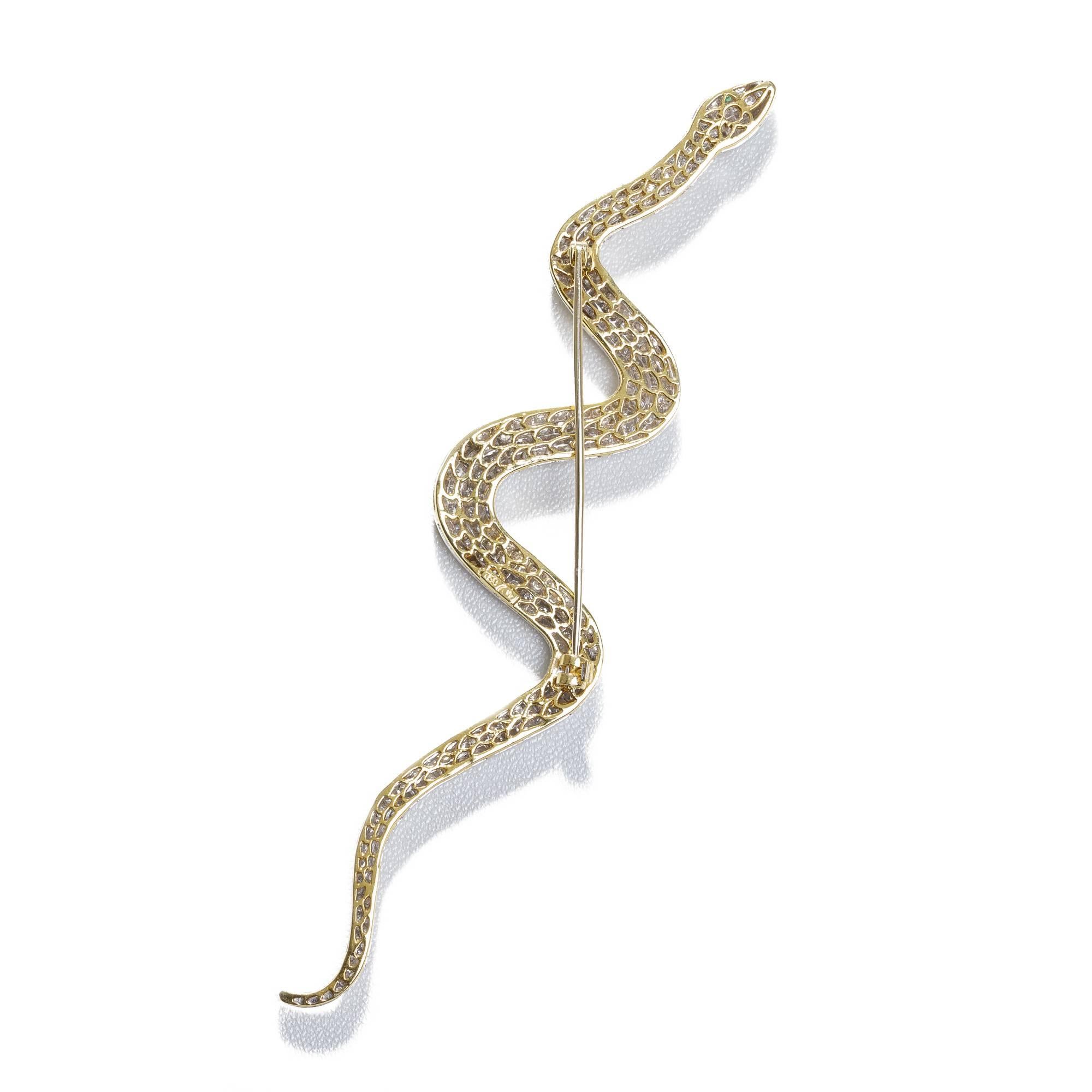 This intricate vintage snake pin is completely handmade, even the clasp. The body of the serpent is made of 18k white and yellow gold and is set with approximately 1.50 ct. of round diamonds. The snake's eyes are set with two cabochon-cut emeralds.
