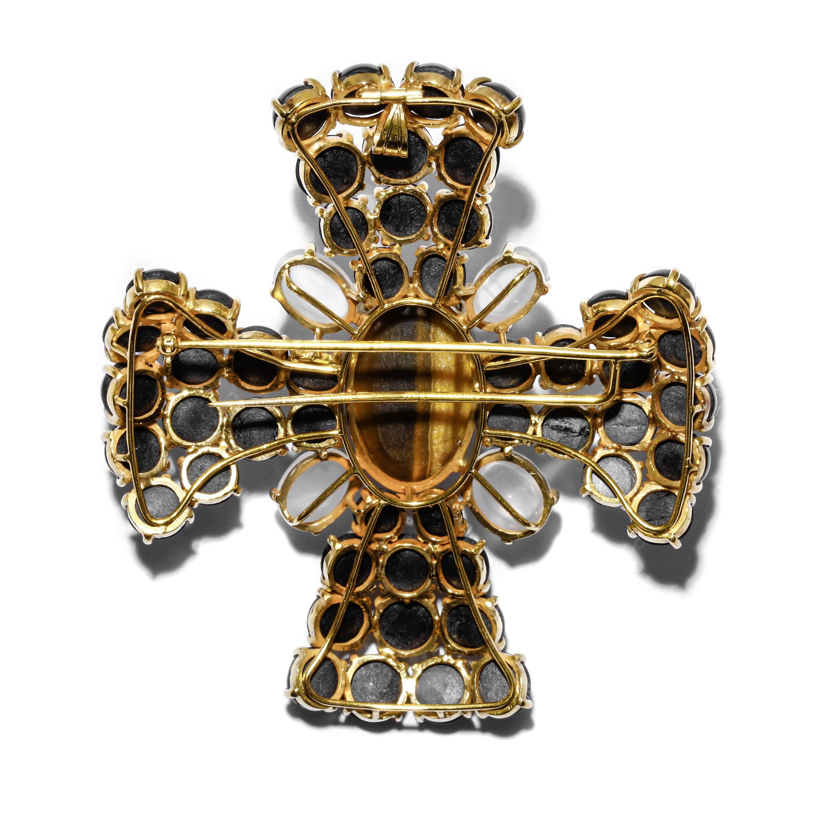 This vintage custom handmade Maltese cross convertible brooch and pendant contains a mix of natural cabochon-cut gemstones that all display optical gemological phenomena. The setting is made of 18k yellow gold. The largest stone in the center is a