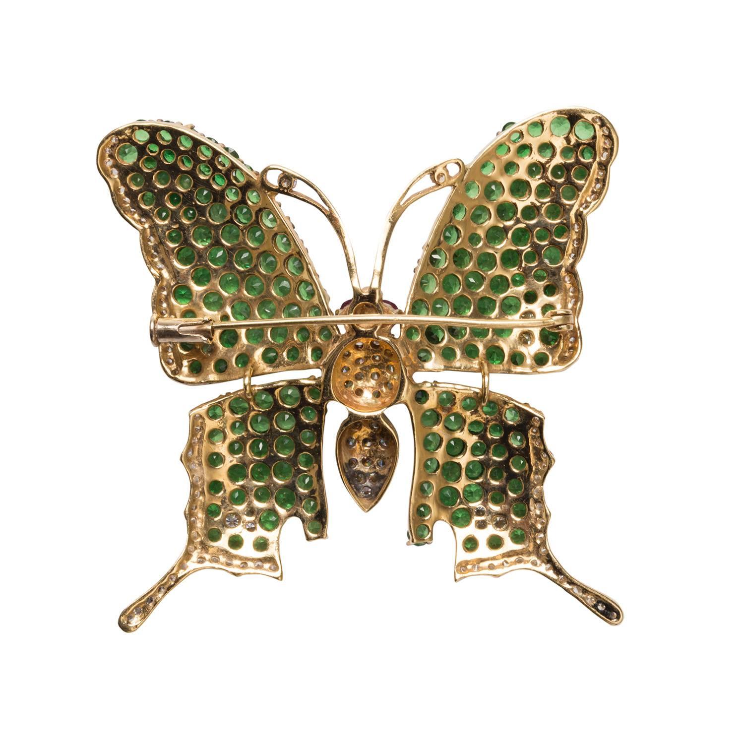 This is a stylized butterfly brooch made of tsavorite, garnet and diamonds set in 18k yellow gold.